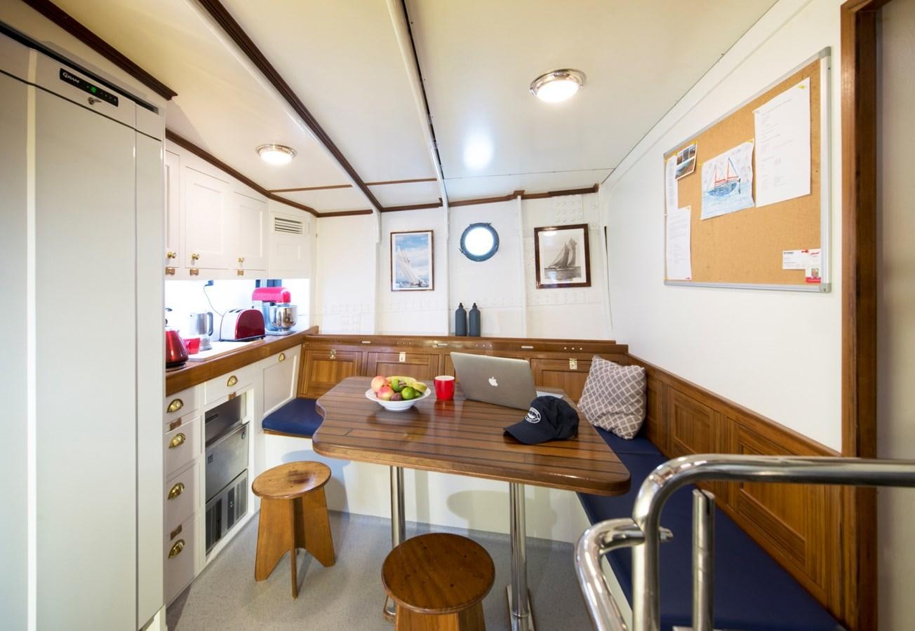 a kitchen with a table and chairs aboard MARIETTE OF 1915 Yacht for Sale