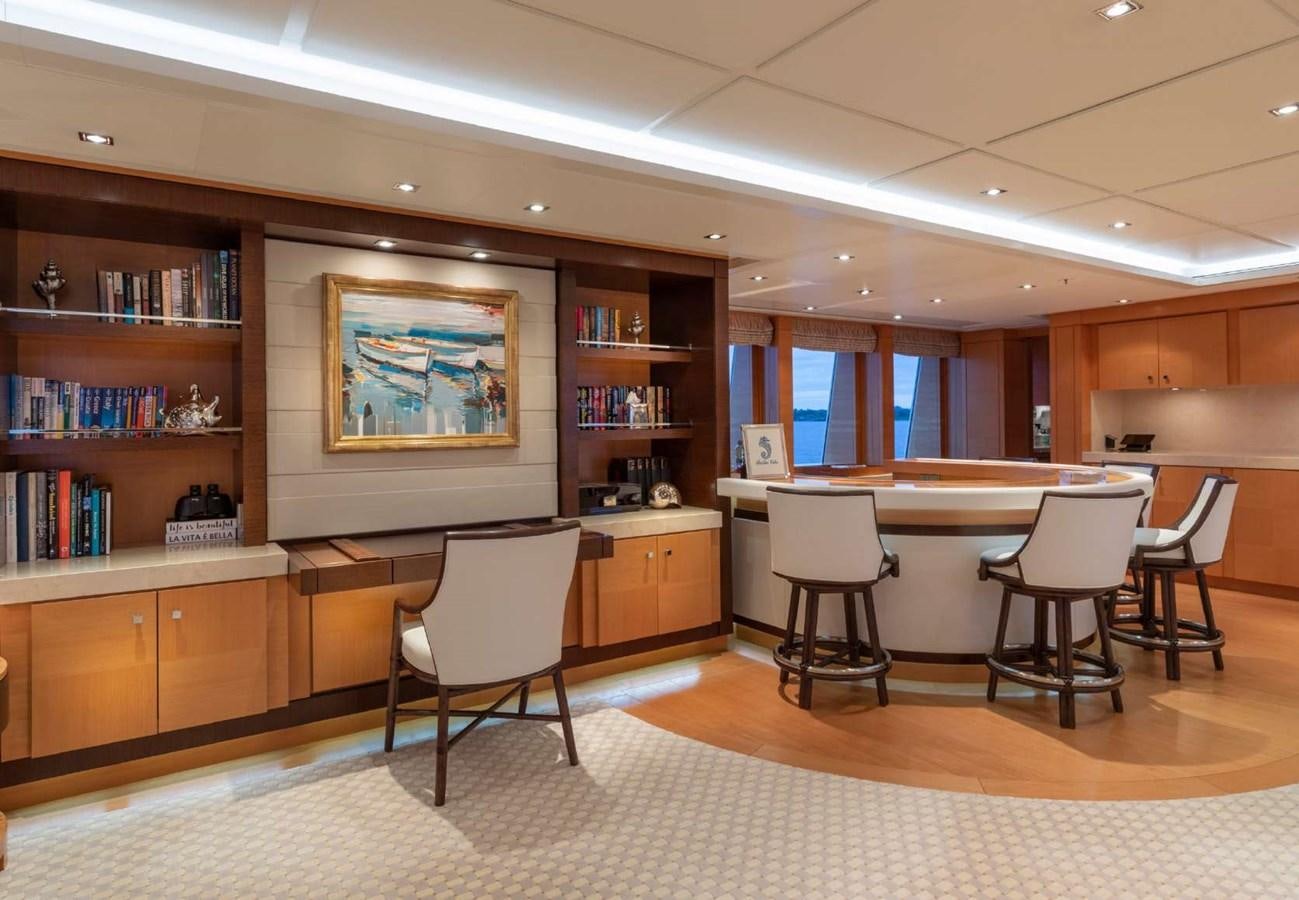 a room with a table chairs and a bookcase aboard BELLA VITA Yacht for Sale