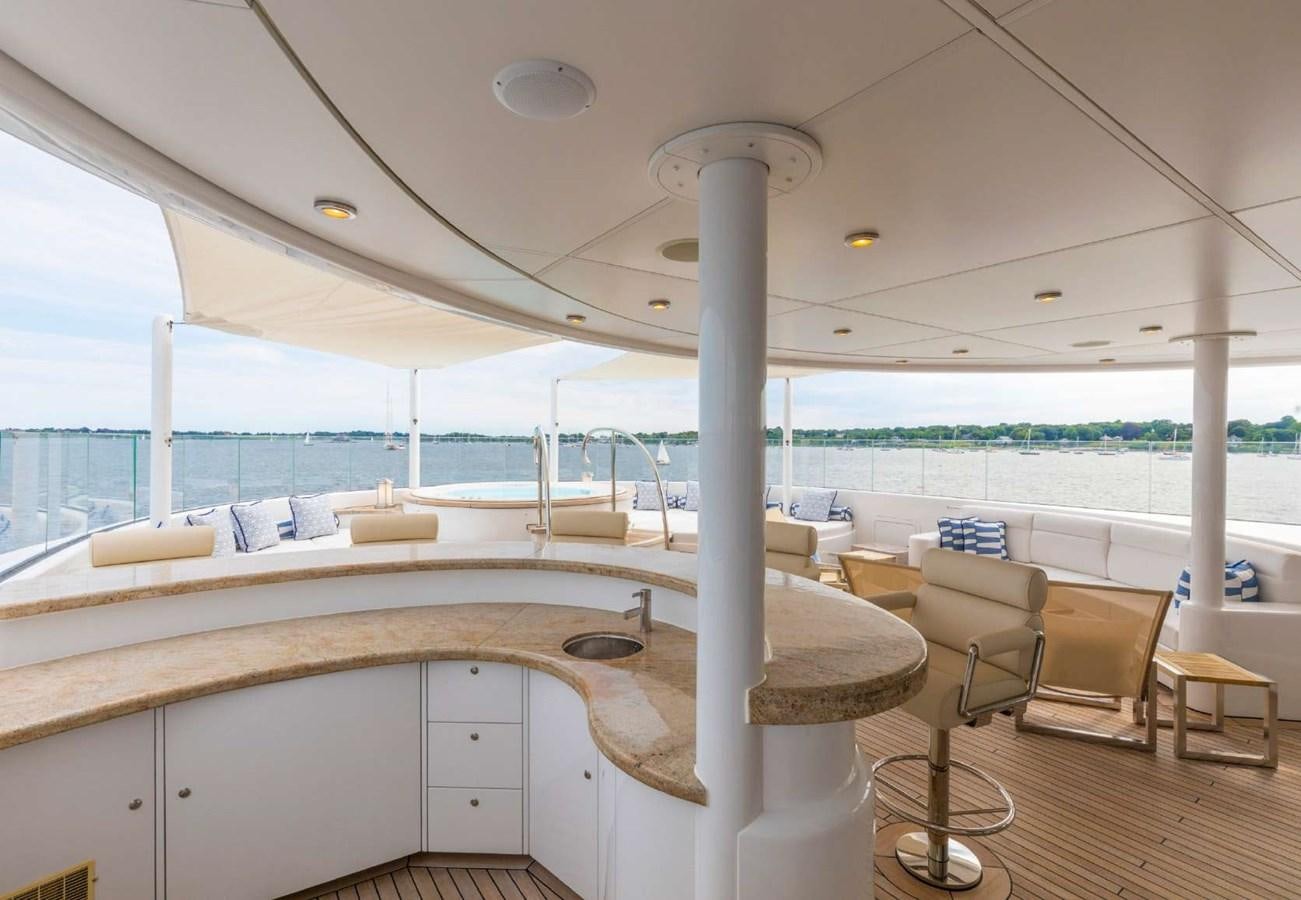 a large white bed with a white canopy and a white table with chairs and a wood floor with aboard BELLA VITA Yacht for Sale