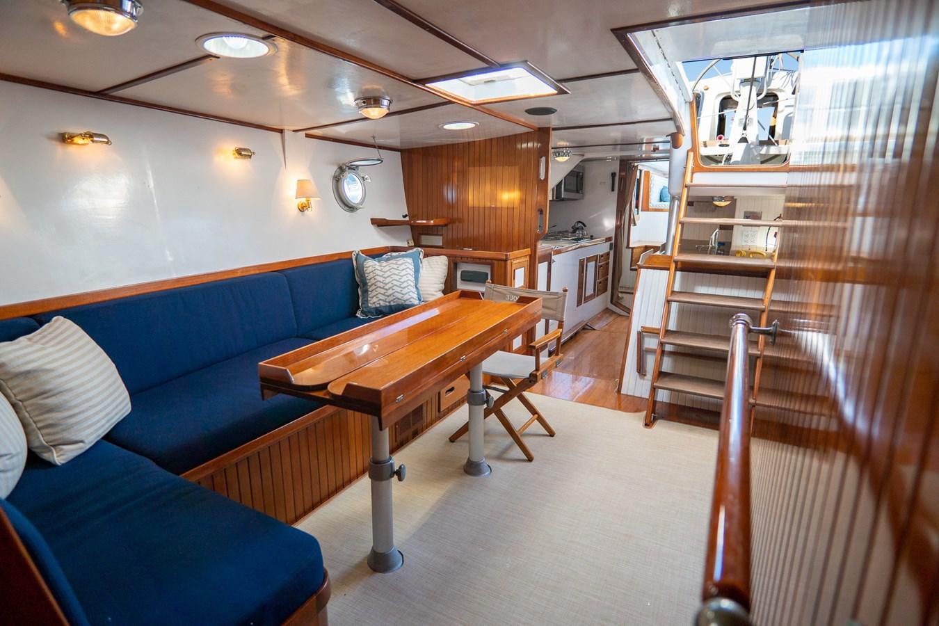 a living room with a blue couch and a wood table aboard PIAFFE Yacht for Sale