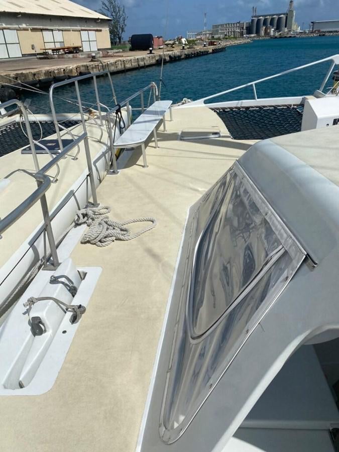 a deck with a pool and a deck with chairs and a building in the background aboard 1996 GOLD COAST GC 70 Yacht for Sale