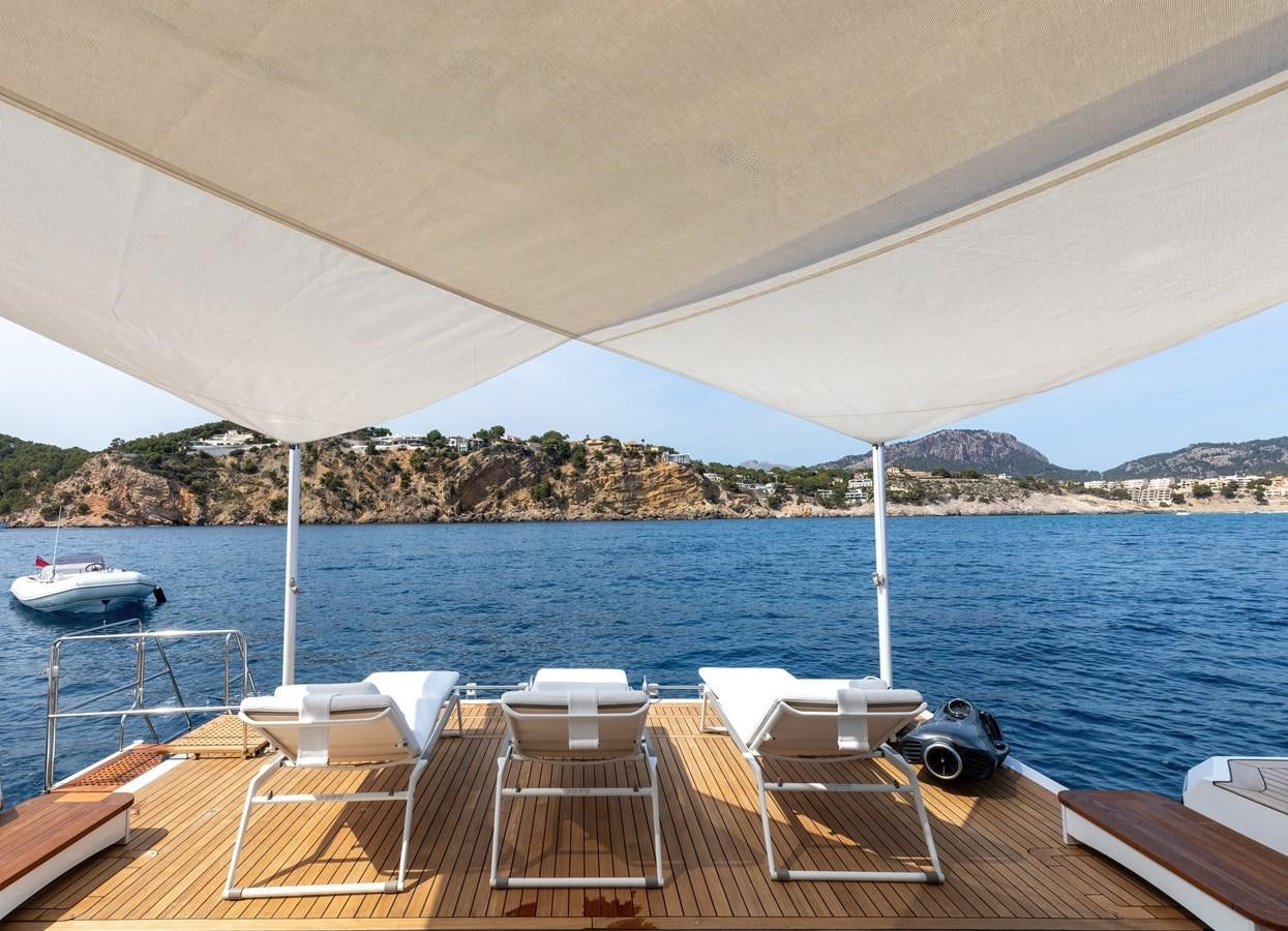 a deck with chairs and tables on it by a body of water aboard NEW WAVES Yacht for Sale