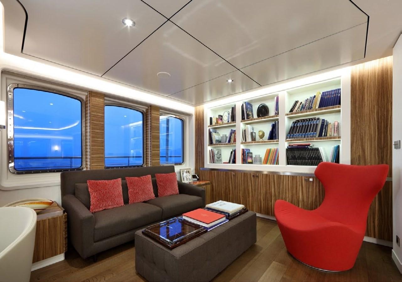 a living room with a red couch and a book shelf aboard YERSIN Yacht for Sale