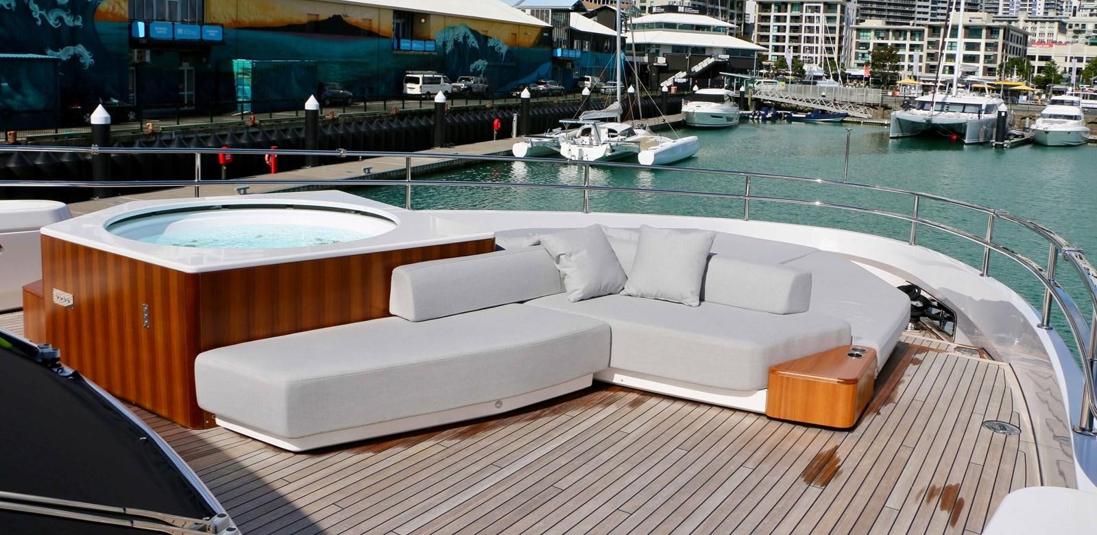 a white couch on a deck by a body of water aboard DB Yacht for Sale