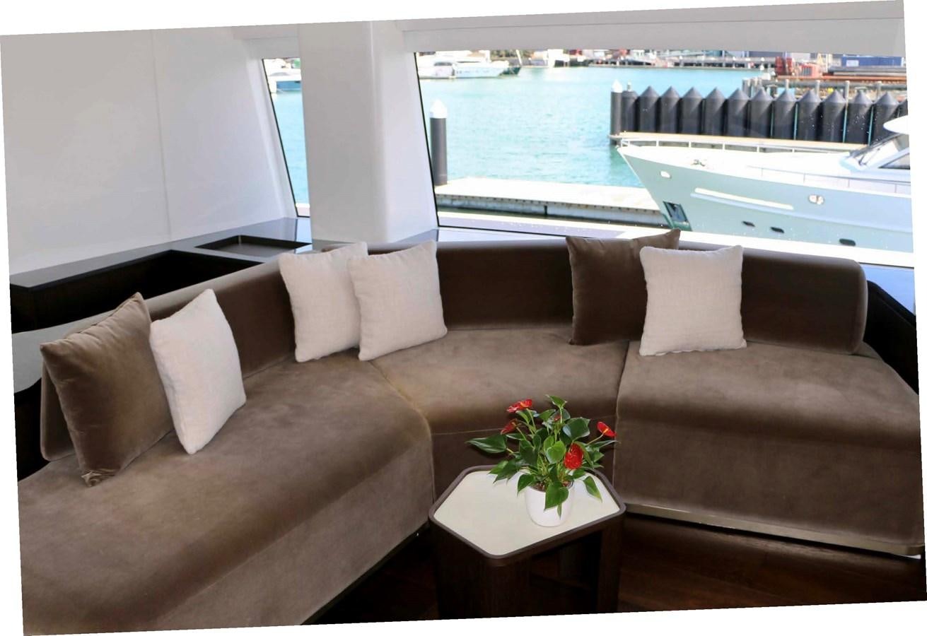 a couch with pillows and a table in front of a window aboard DB Yacht for Sale