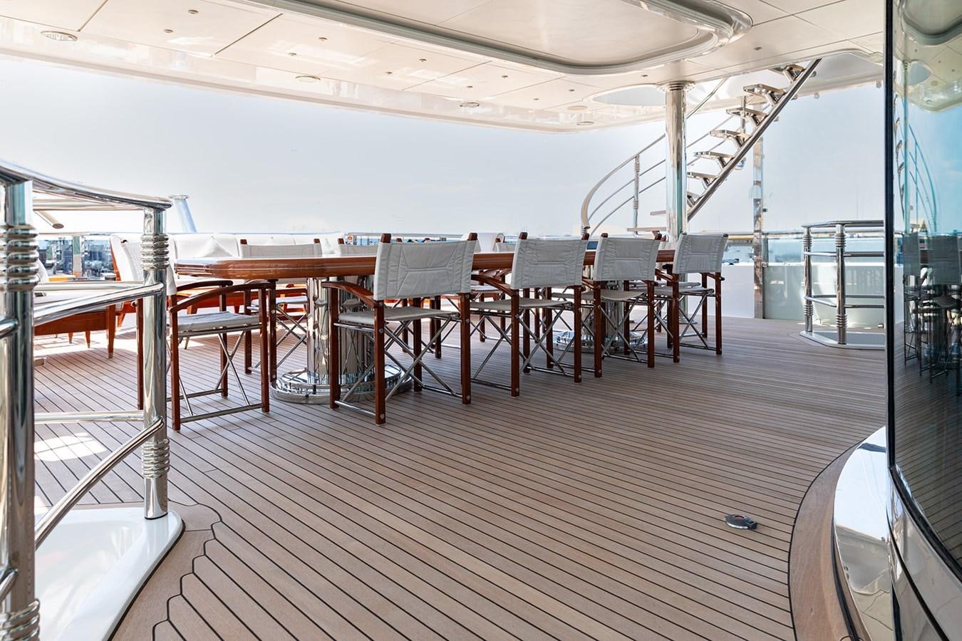 a long wooden deck with tables and chairs aboard QUEEN MAVIA Yacht for Sale