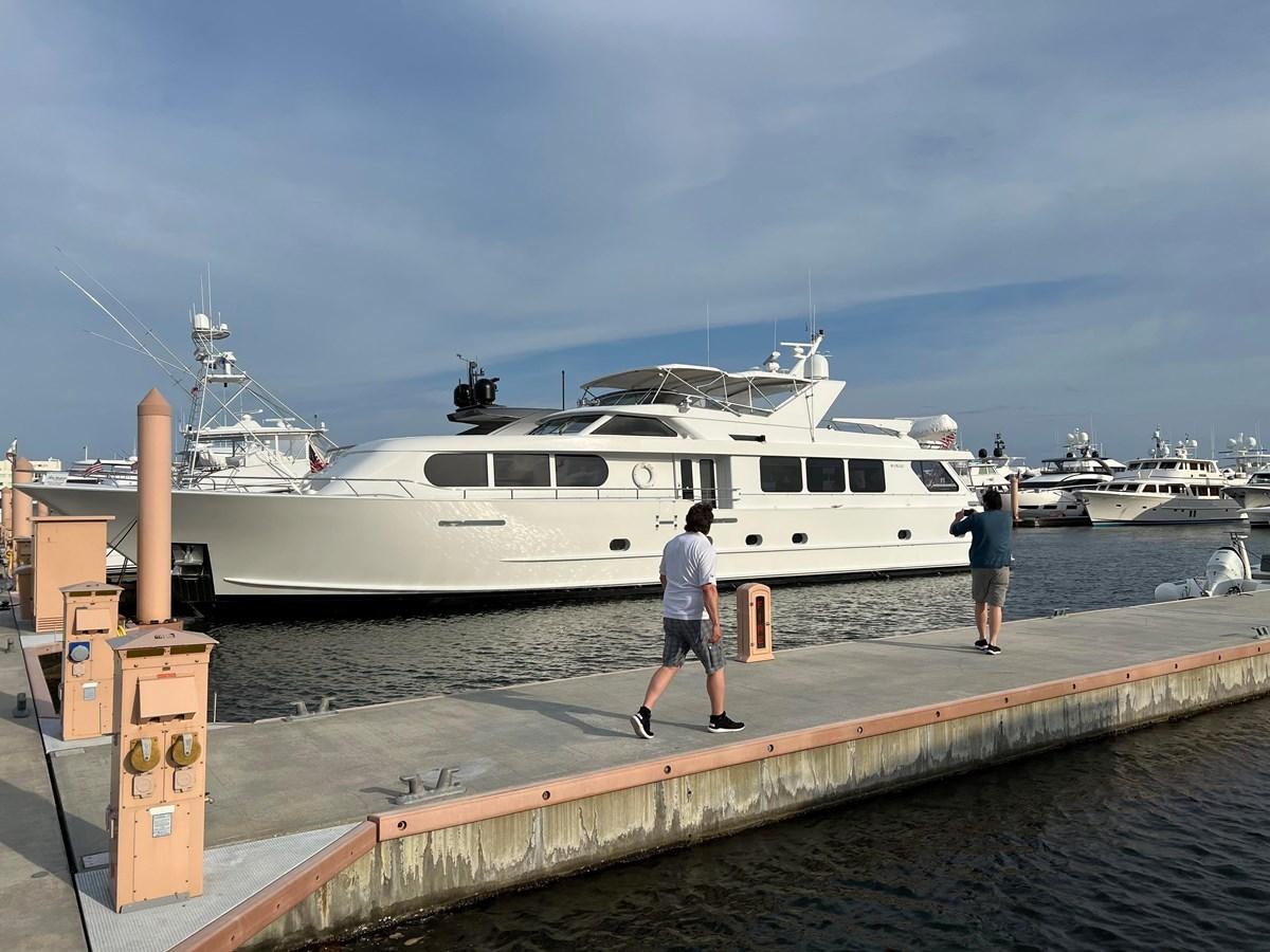 a person walking on a dock next to a large white boat aboard 2001 BROWARD RAISED PILOTHOUSE MY Yacht for Sale