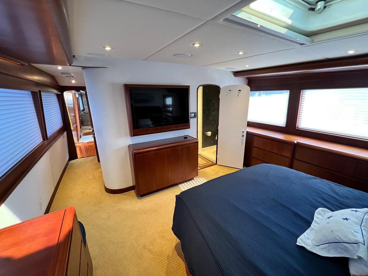 a bedroom with a bed and a tv aboard 2001 BROWARD RAISED PILOTHOUSE MY Yacht for Sale