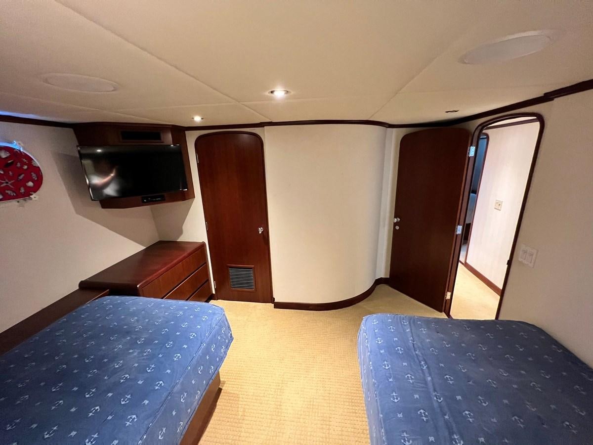 a room with a bed and a television aboard 2001 BROWARD RAISED PILOTHOUSE MY Yacht for Sale