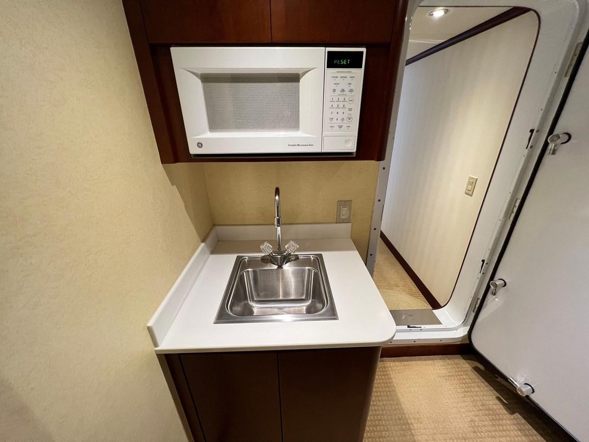a microwave oven and a sink in a kitchen aboard 2001 BROWARD RAISED PILOTHOUSE MY Yacht for Sale