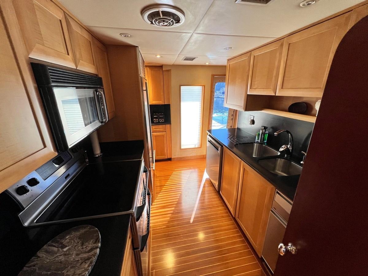 a kitchen with wooden cabinets aboard 2001 BROWARD RAISED PILOTHOUSE MY Yacht for Sale