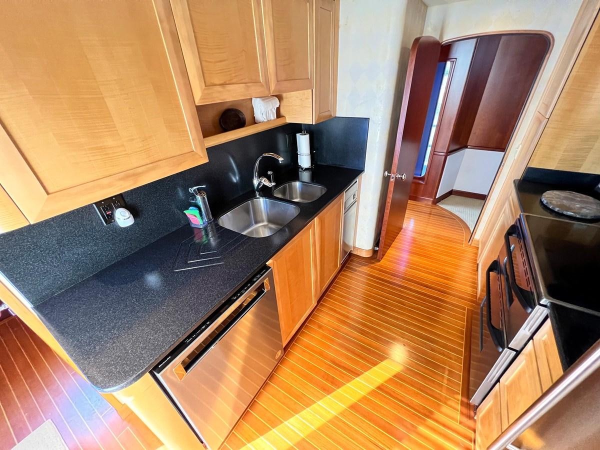 a kitchen with black counter tops aboard 2001 BROWARD RAISED PILOTHOUSE MY Yacht for Sale