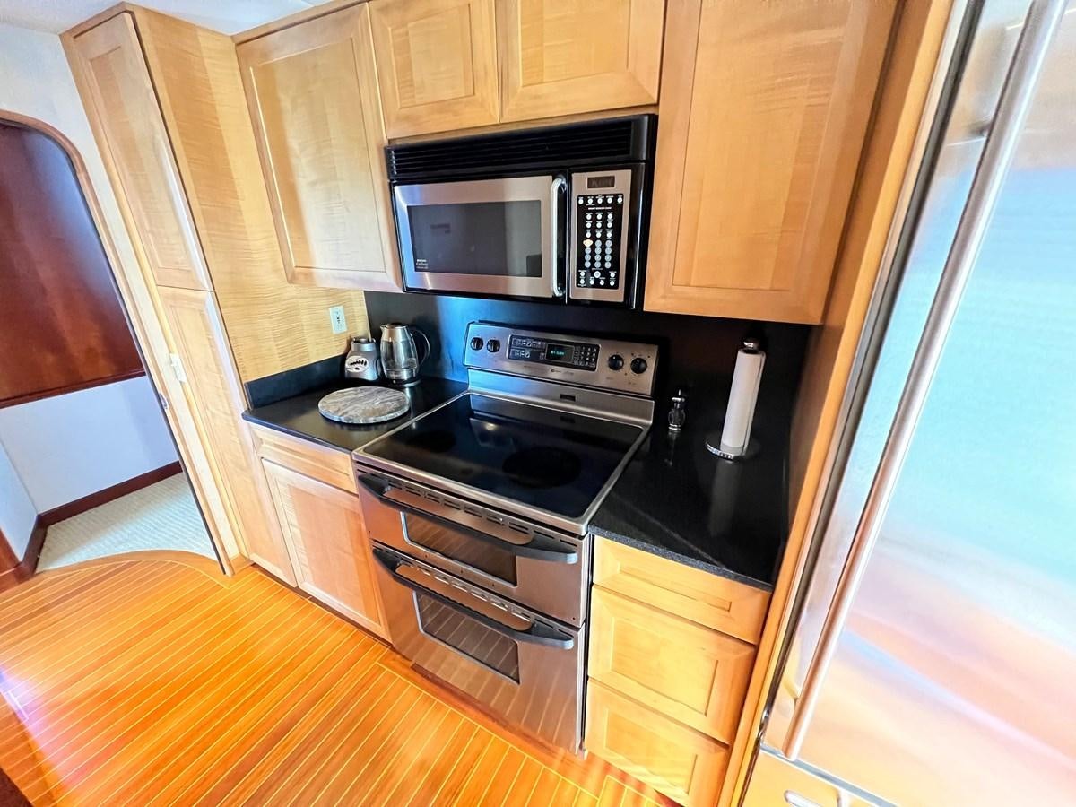 a kitchen with wooden cabinets aboard 2001 BROWARD RAISED PILOTHOUSE MY Yacht for Sale