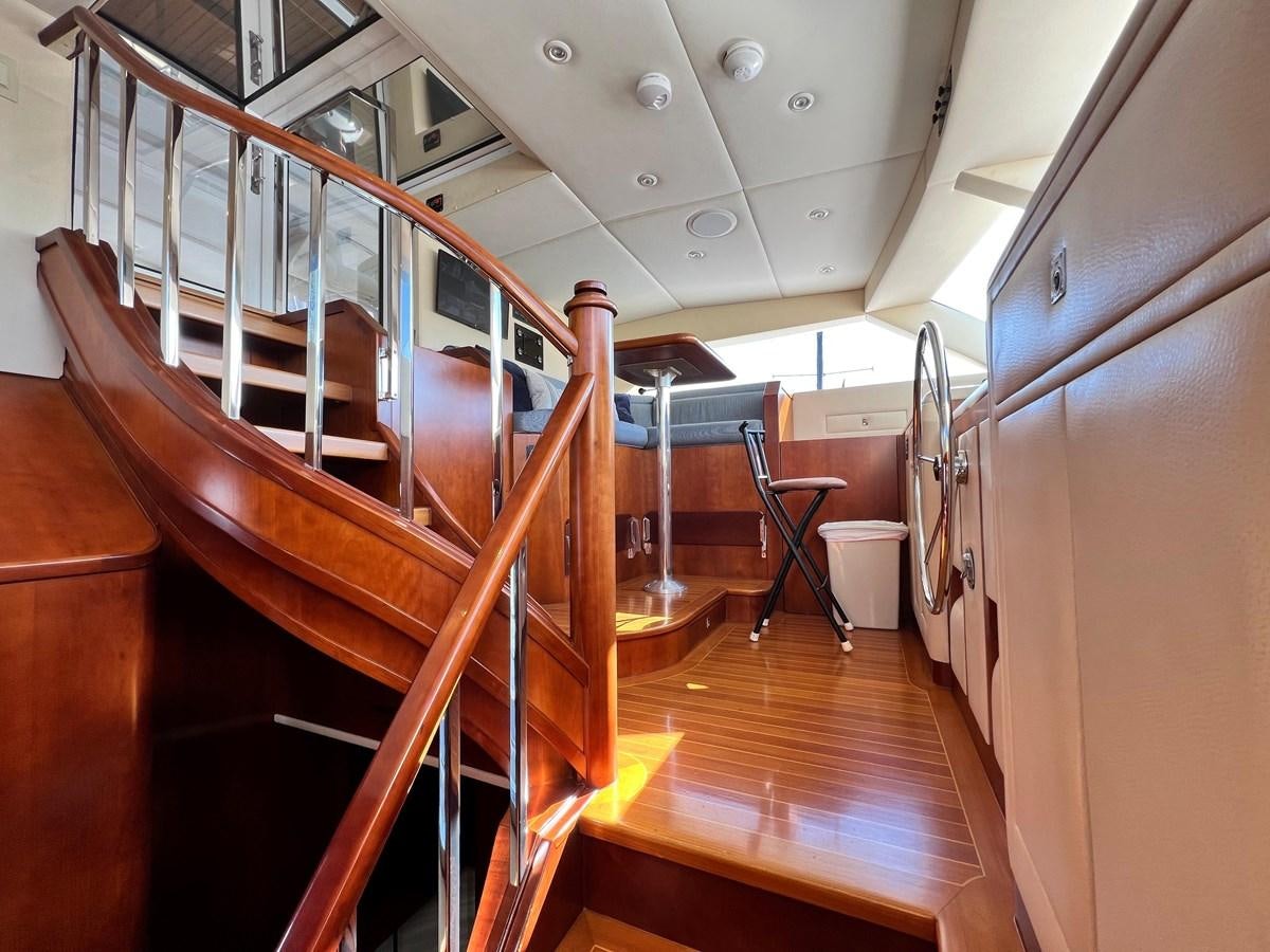 a large room with wooden stairs aboard 2001 BROWARD RAISED PILOTHOUSE MY Yacht for Sale