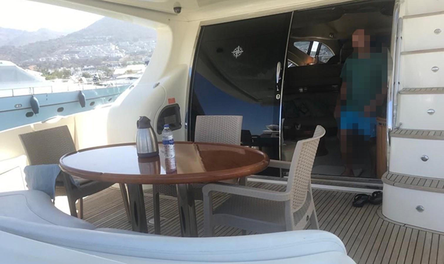 a table with chairs and a bottle on it aboard 68 PLUS Yacht for Sale