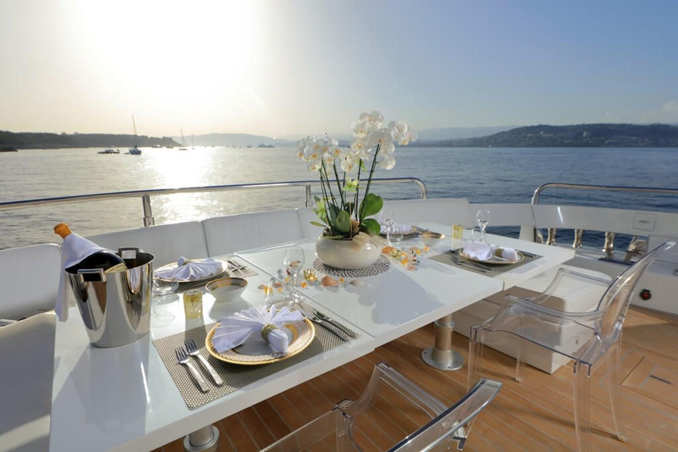a table with plates and flowers on it aboard BAIA 100 Yacht for Sale