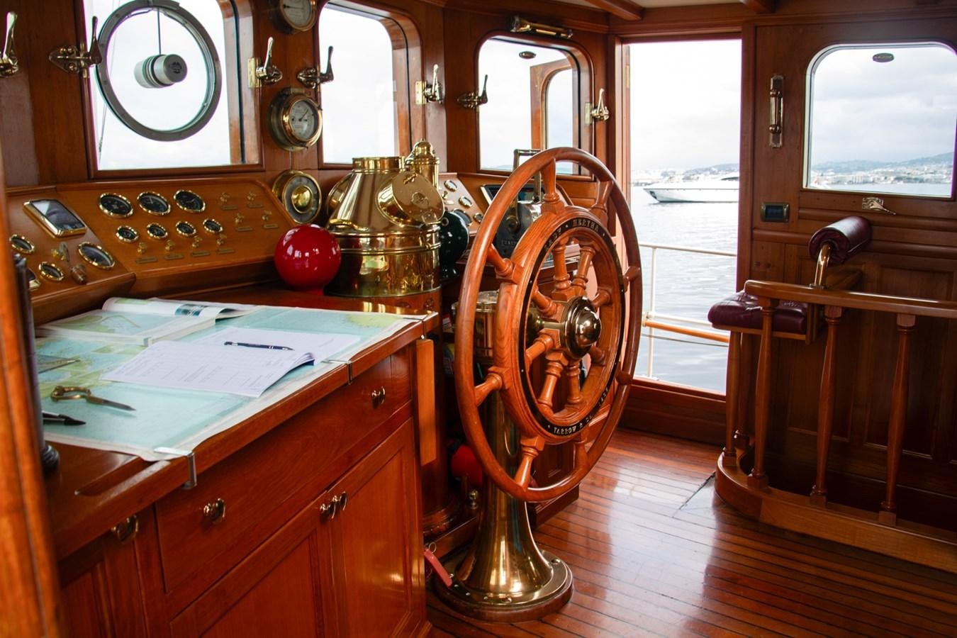 a room with a wood table and a large wheel aboard LADY HERTHA Yacht for Sale