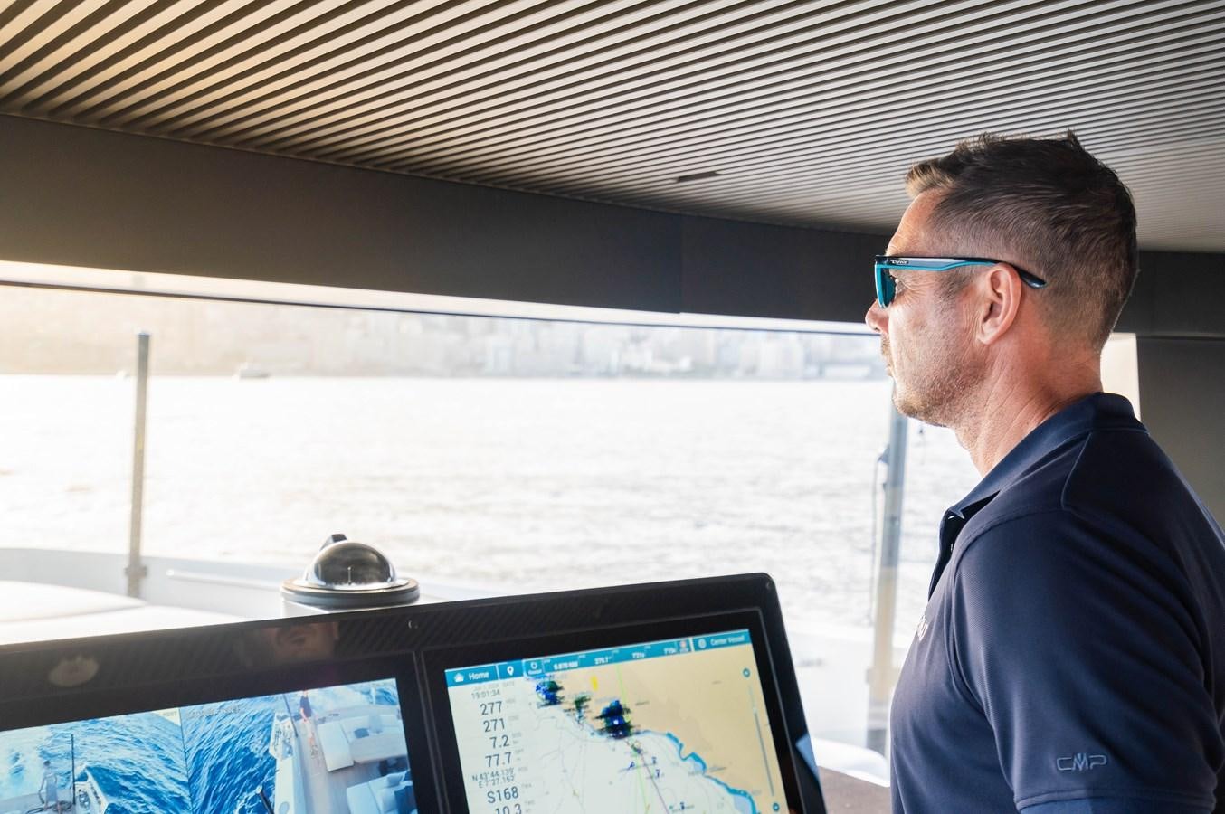 a man looking at a computer screen aboard ANMAX Yacht for Sale