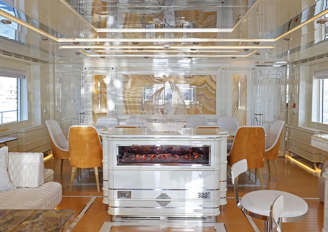 a room with a fireplace and chairs aboard DOMENIKA Yacht for Sale
