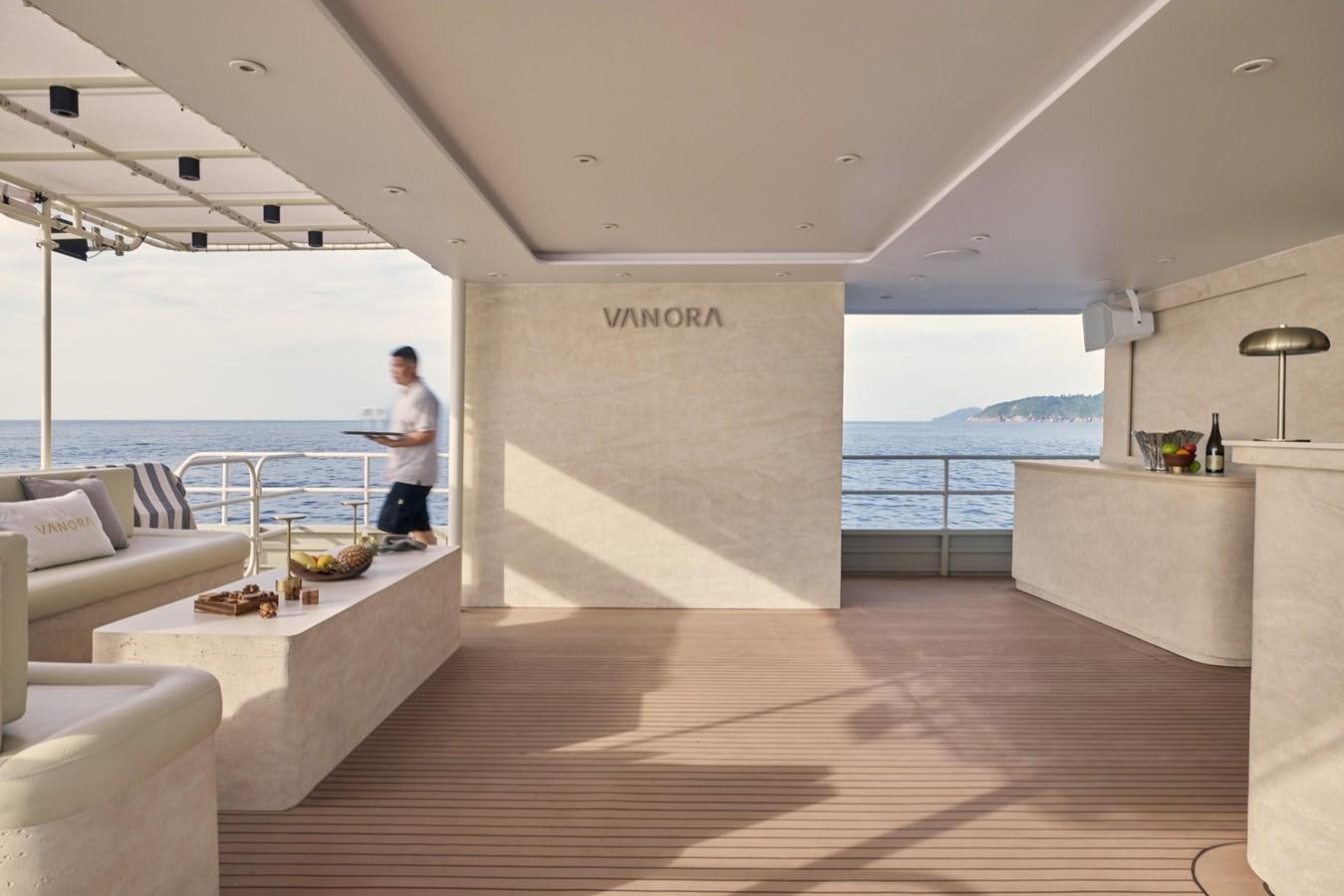a person standing on a wood deck next to a large body of water aboard VANORA Yacht for Sale