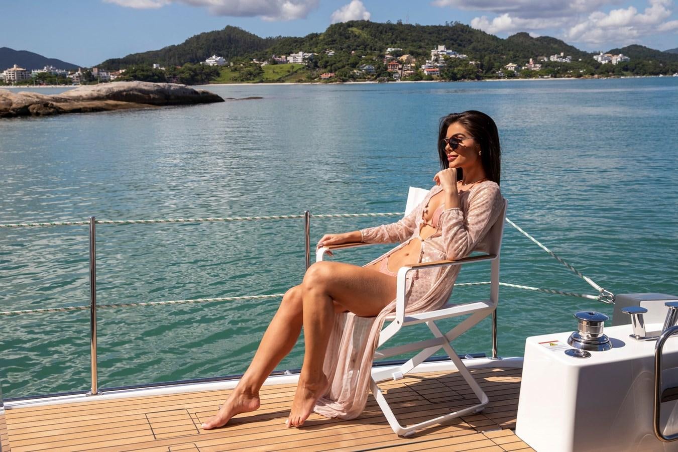 a woman sitting on a chair on a dock by the water aboard SCHAEFER 660 Yacht for Sale
