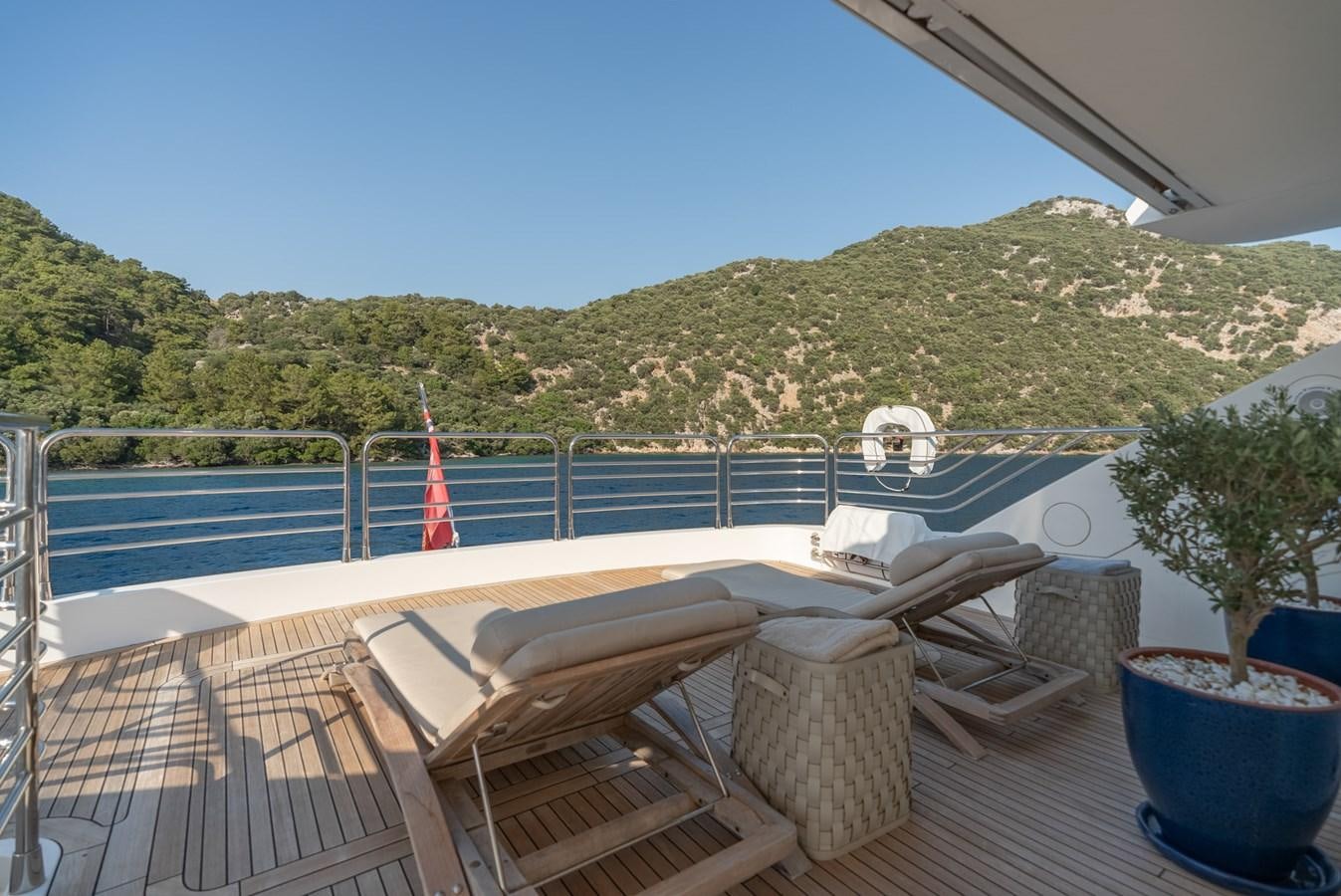 a deck with chairs and a hill in the background aboard ROUND MIDNIGHT Yacht for Sale