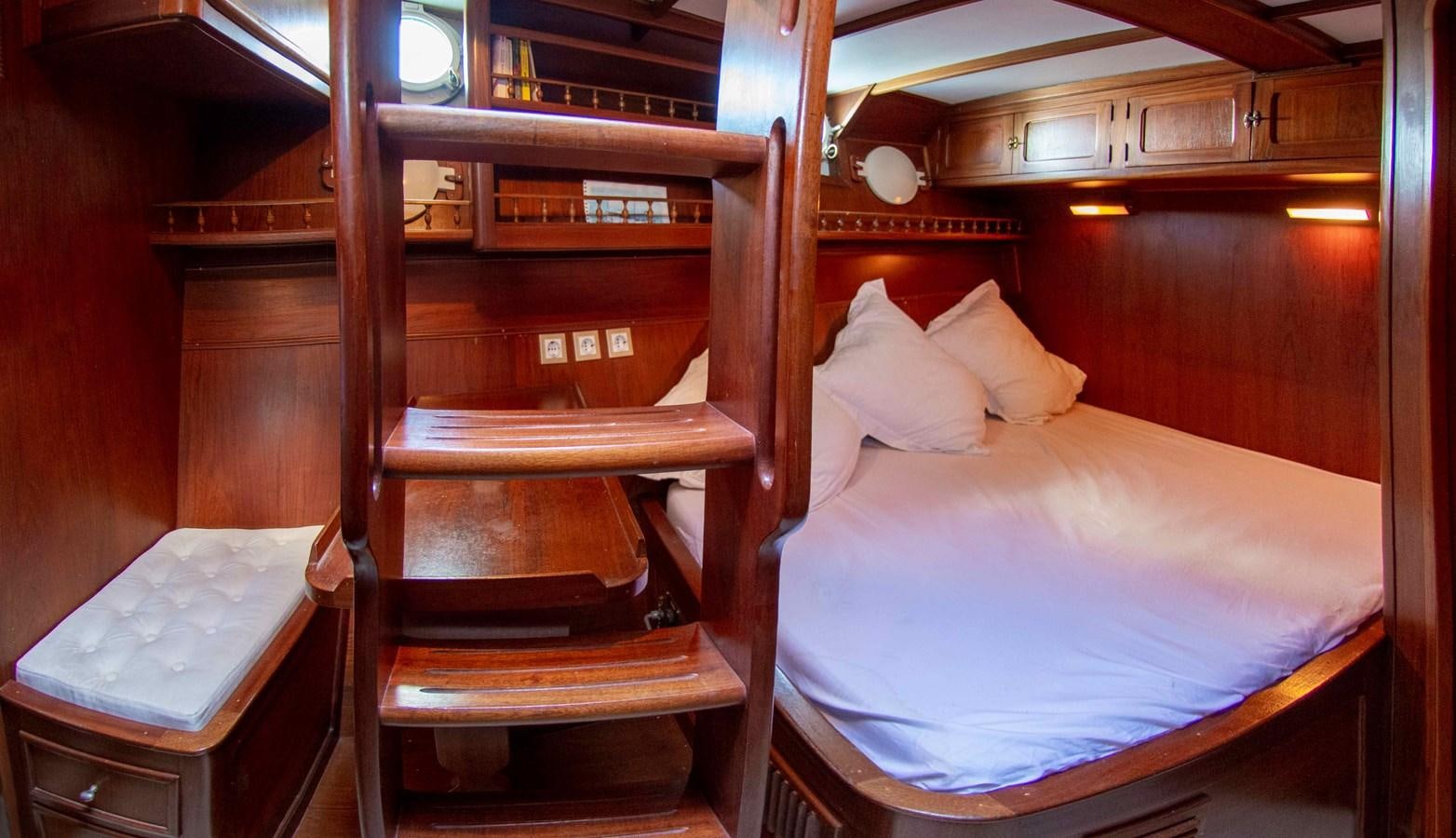a bed with a chair and a table in a room aboard FOREVER Yacht for Sale