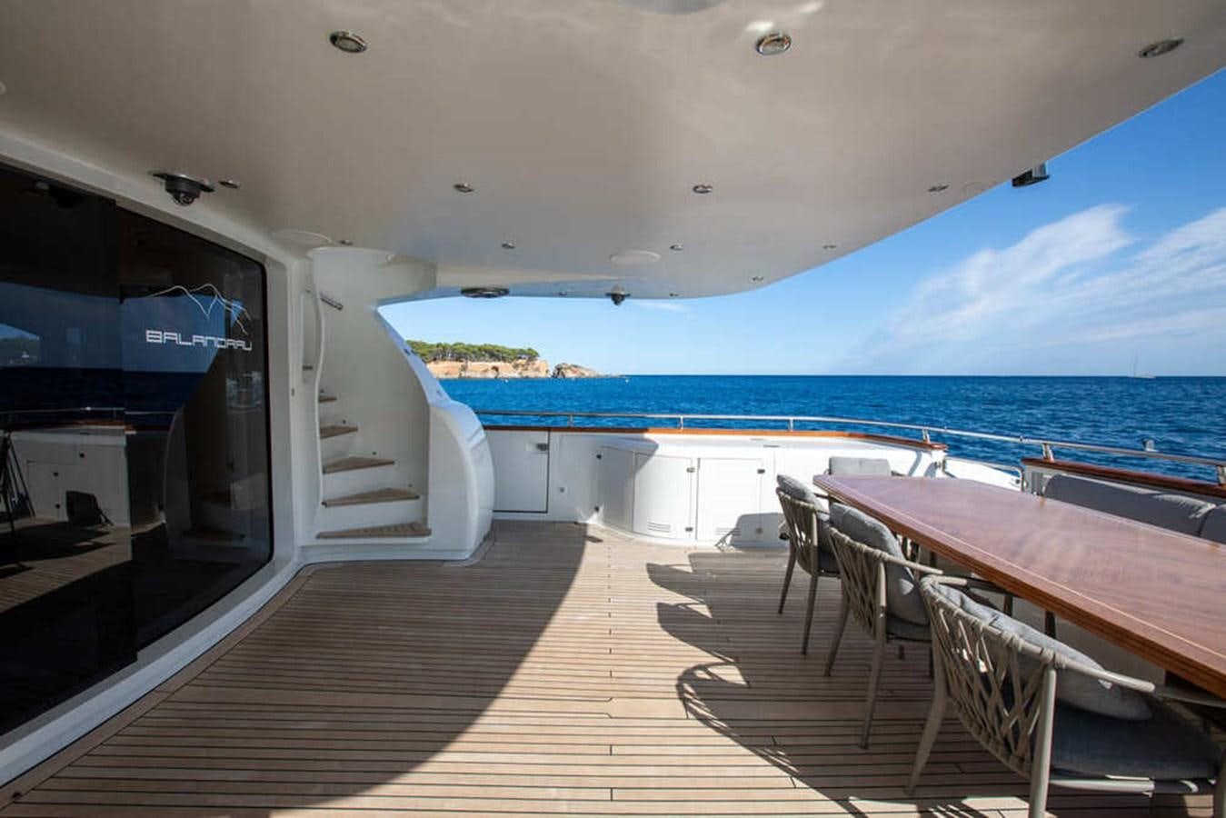 a deck with chairs and tables on it by a body of water aboard BALANDRAU Yacht for Sale