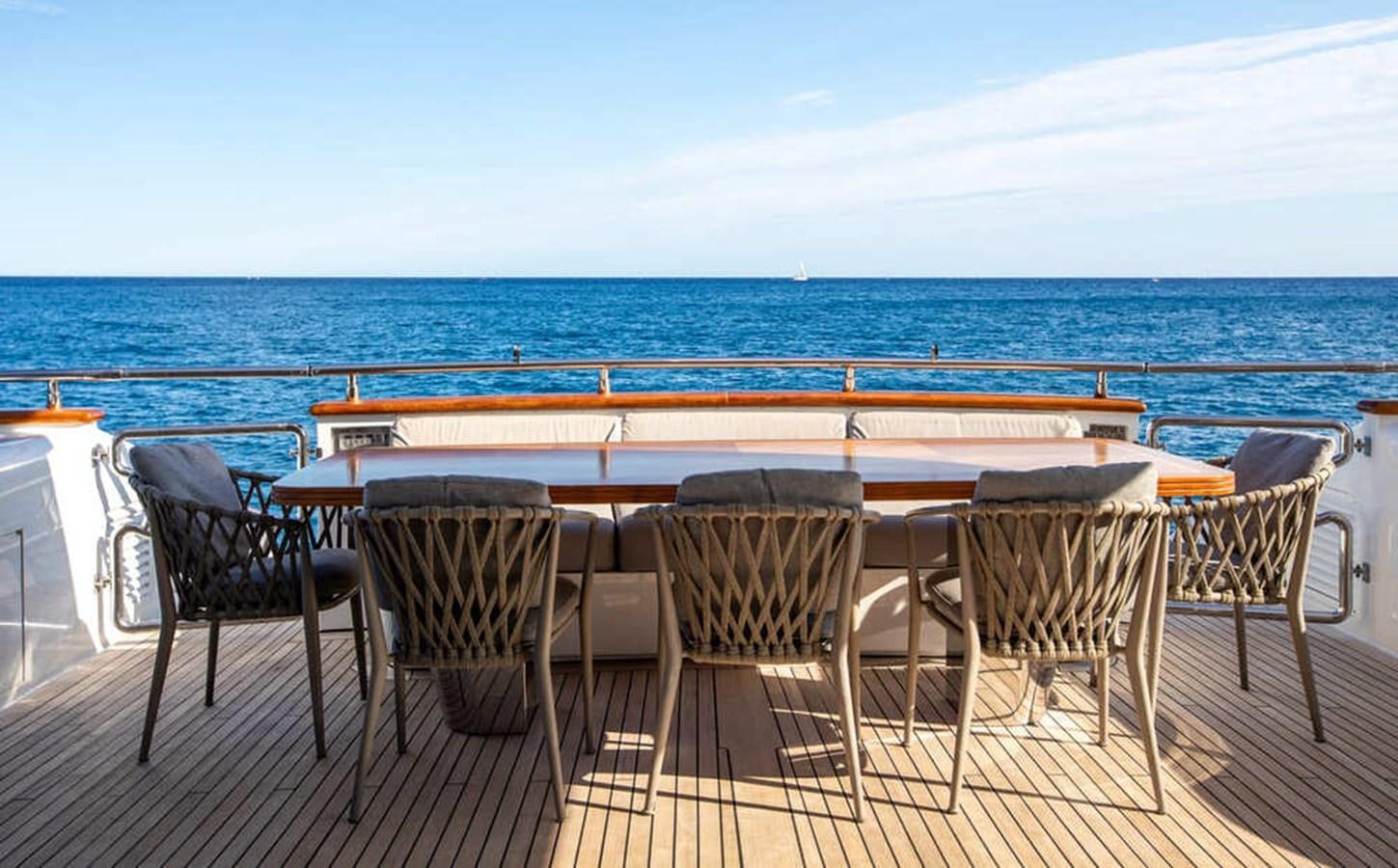 a table and chairs on a deck overlooking the ocean aboard BALANDRAU Yacht for Sale