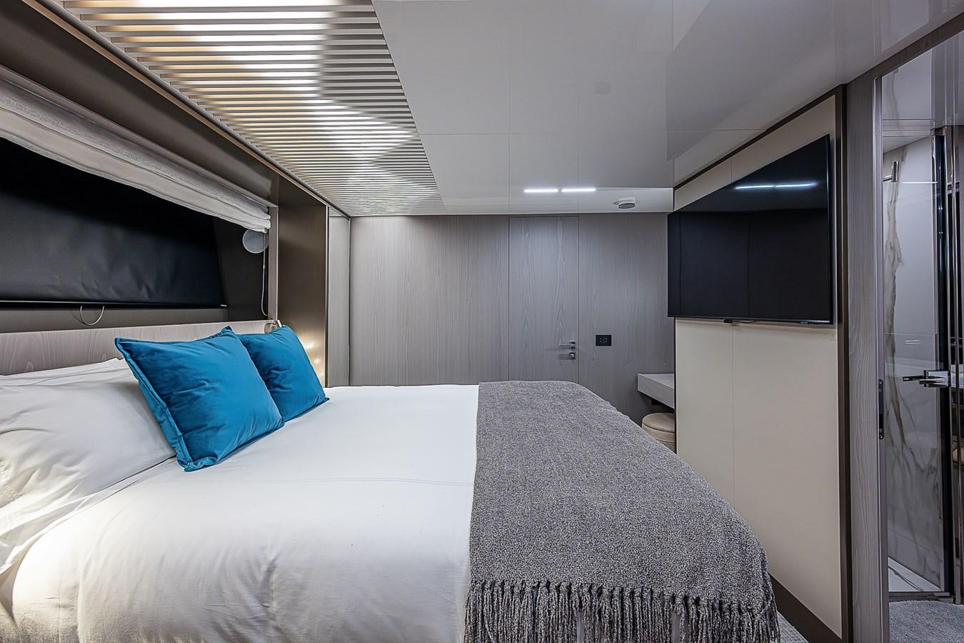 a bed with a white sheet and blue pillows aboard DANDY 2021 FERRETTI 850 @ AVENTURA Yacht for Sale
