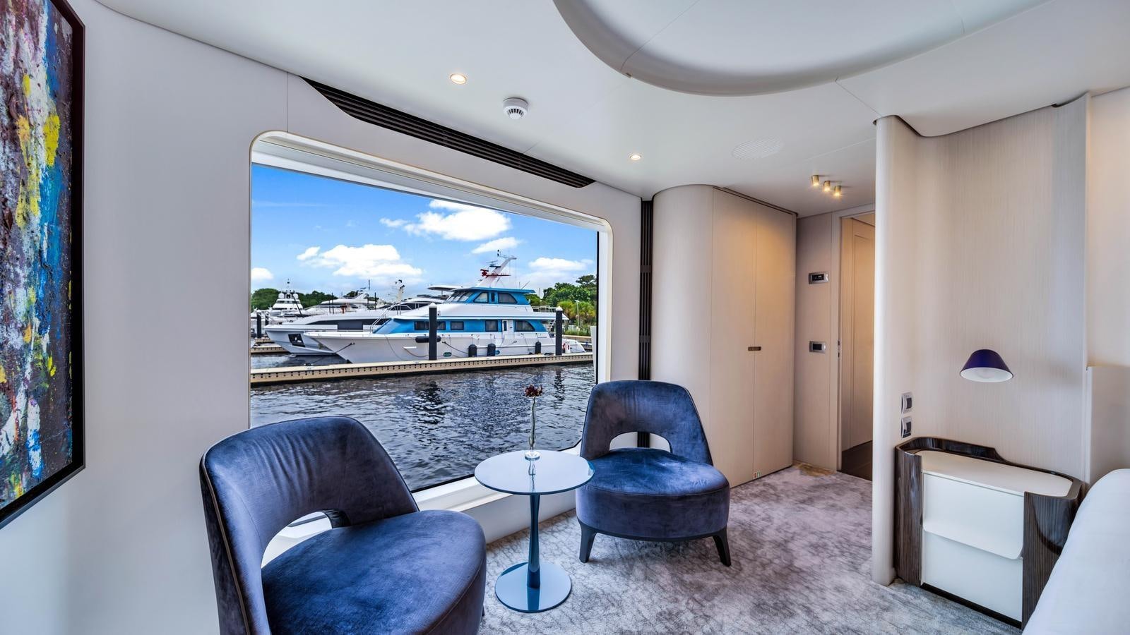 a room with a table chairs and a painting on the wall aboard ONE & ONLY Yacht for Sale