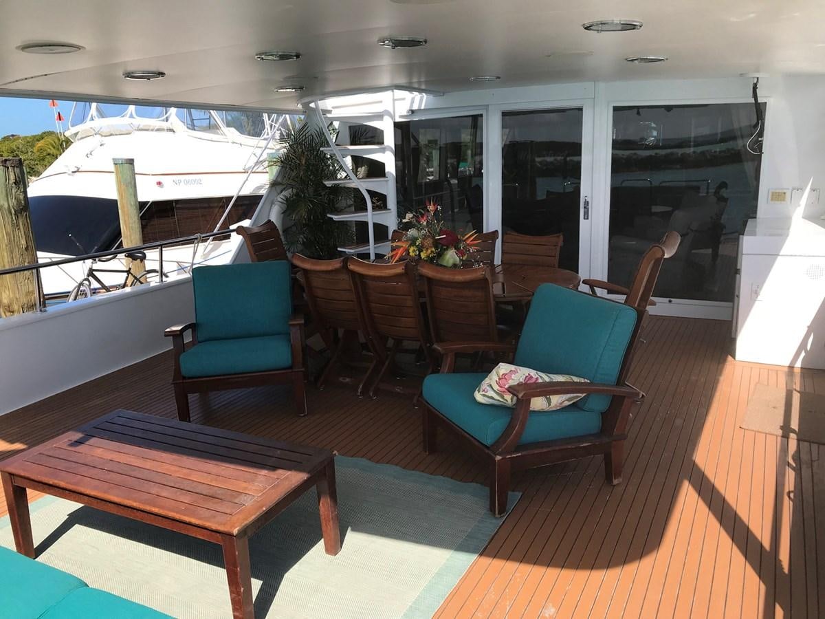 a room with a table chairs and a boat in the background aboard MON SHERI Yacht for Sale