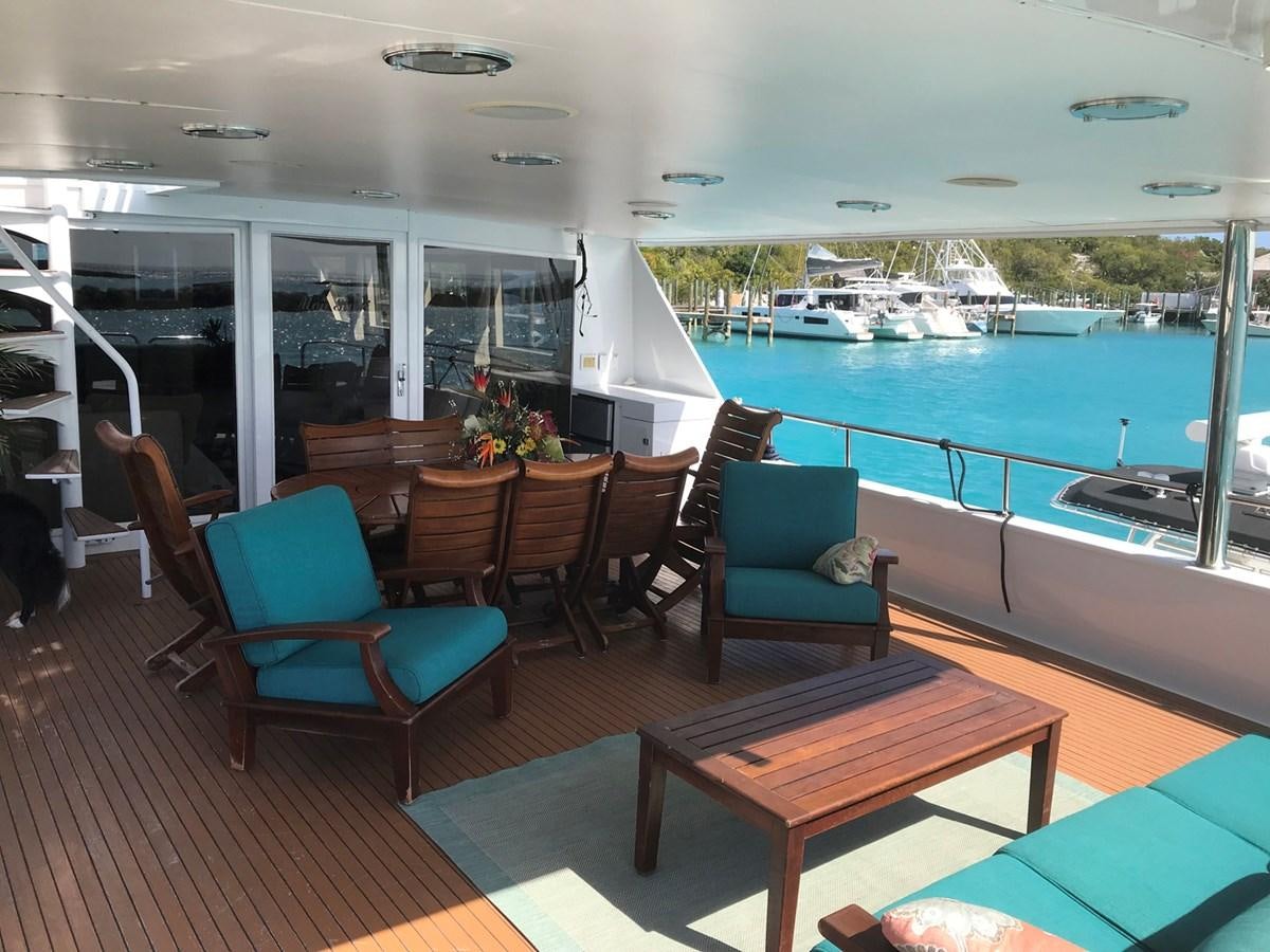 a room with a table chairs and a boat in the water aboard MON SHERI Yacht for Sale