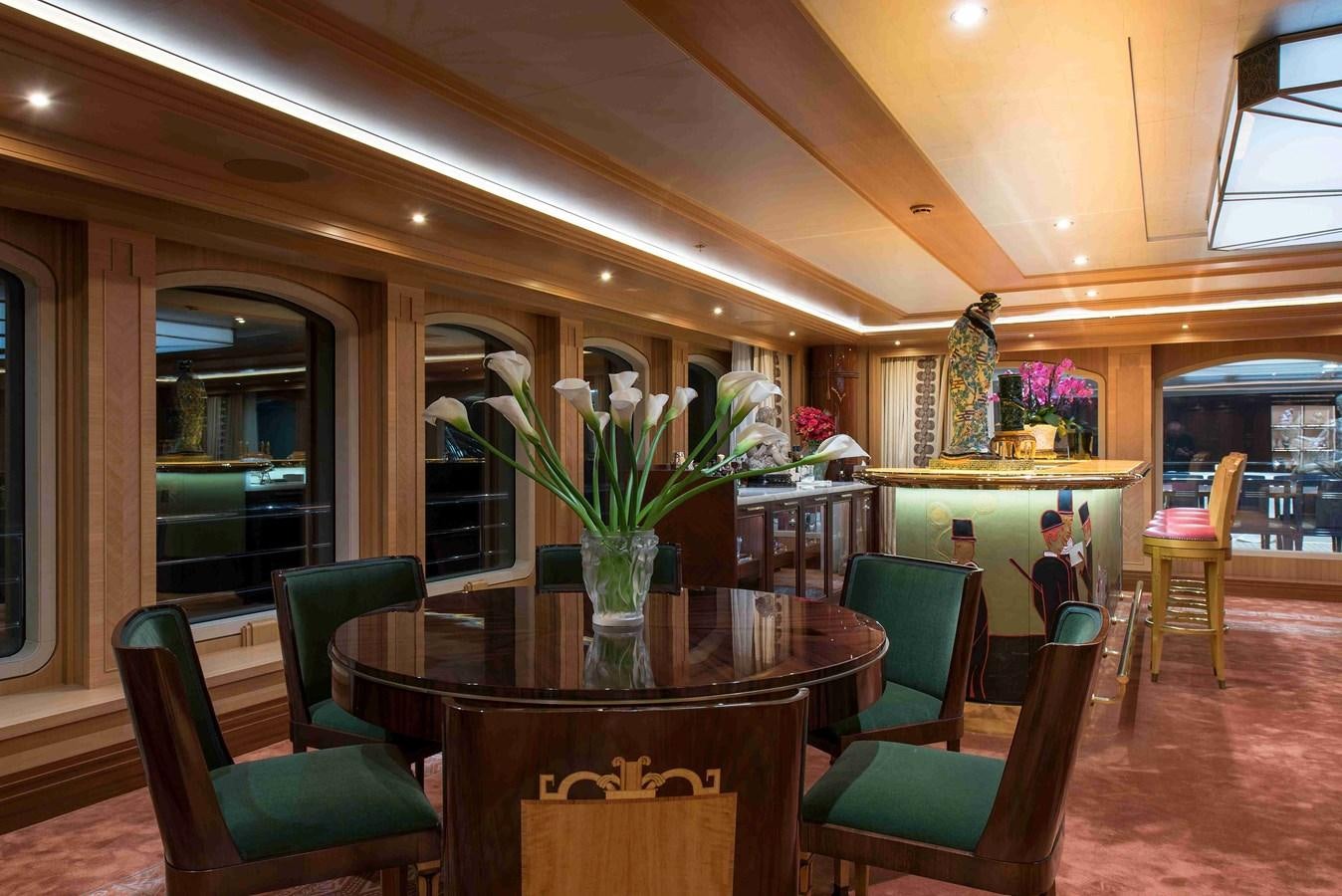 a dining room with green chairs and flowers aboard AURORA Yacht for Sale