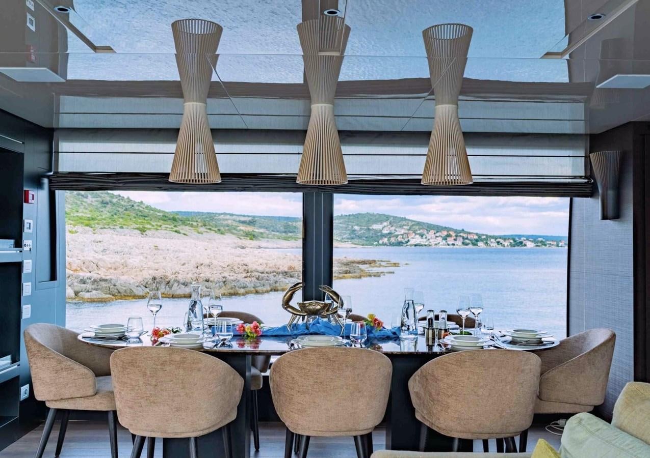 a table with chairs and a large window with a view of the mountains aboard ASYMMETRIC Yacht for Sale