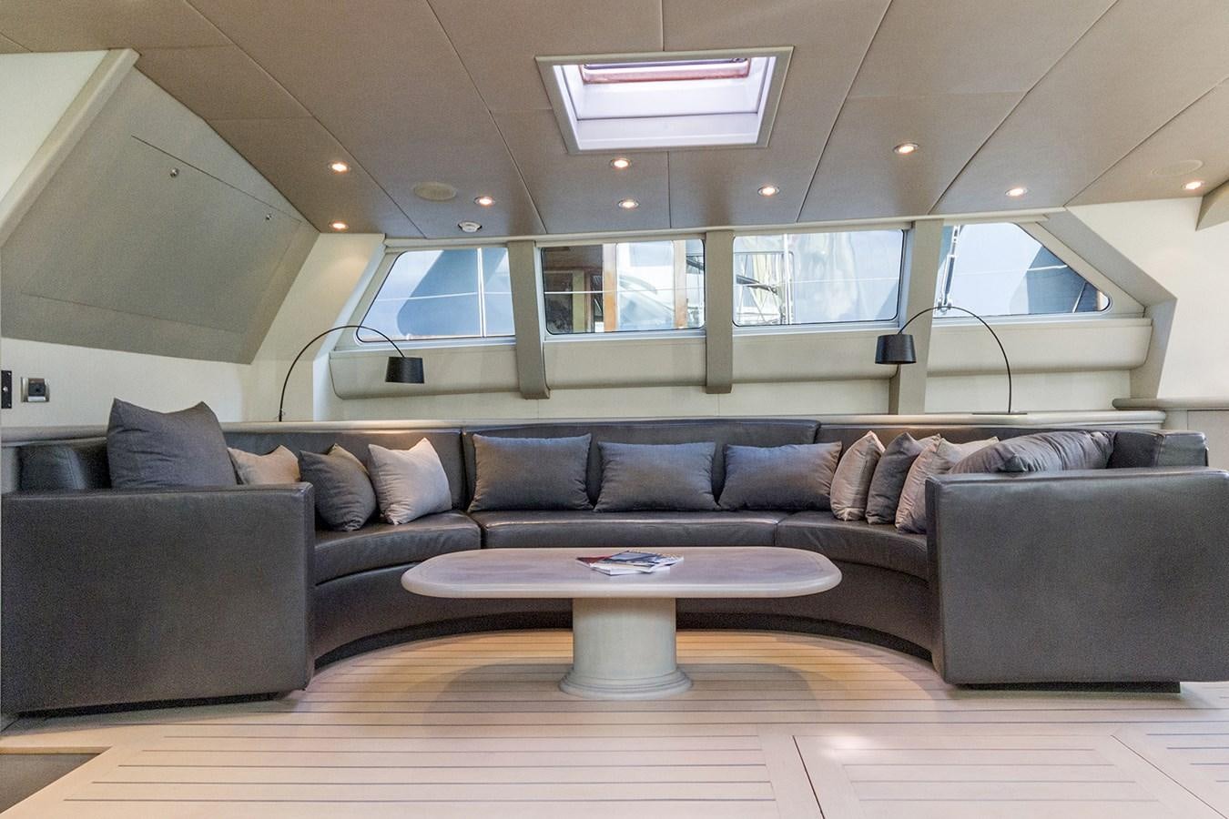 a couch and a coffee table in a room with glass walls aboard IEMANJA Yacht for Sale