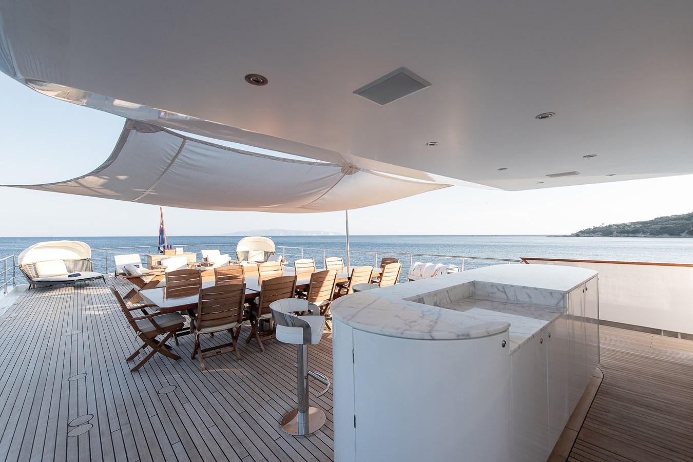 a deck with chairs and tables on it by the water aboard KORU Yacht for Sale
