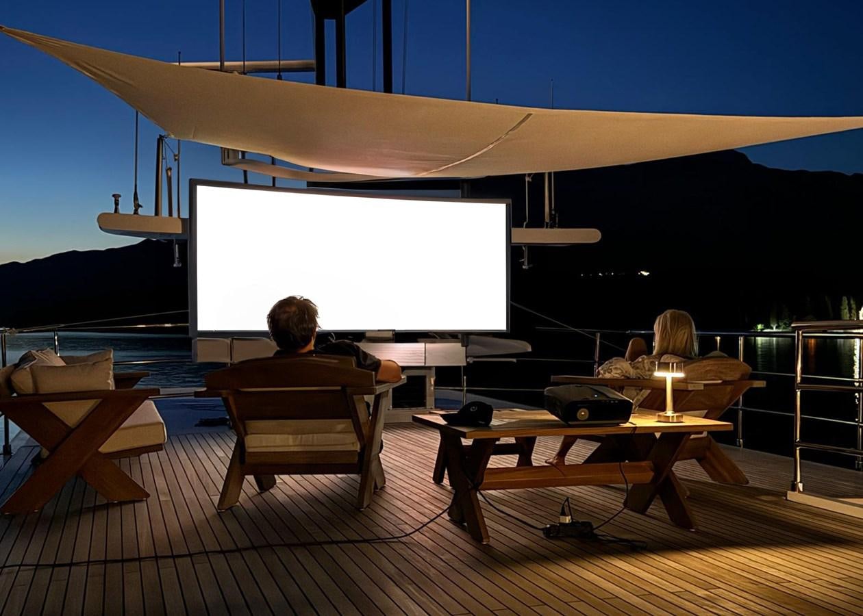 a person sitting at a table in front of a large screen aboard KORU Yacht for Sale