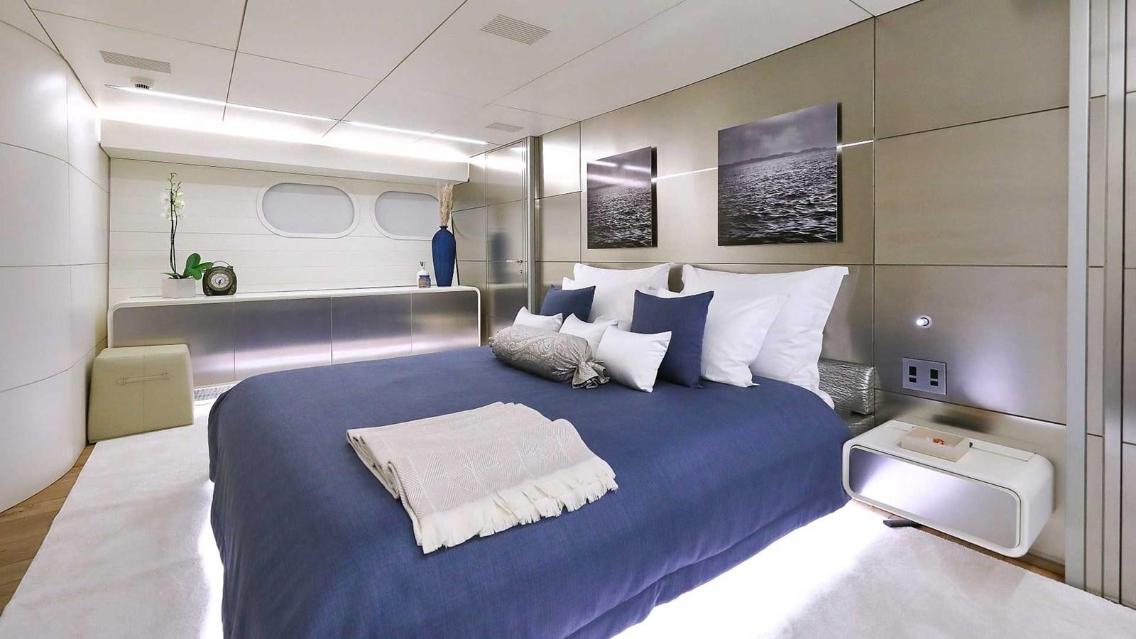 a large bed with blue sheets aboard ANAVI Yacht for Sale