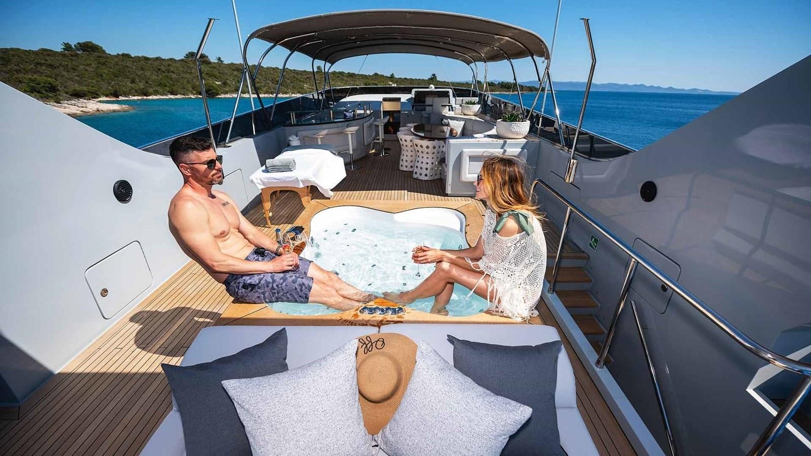 a man and woman sitting on a lounge chair on a boat aboard ANAVI Yacht for Sale