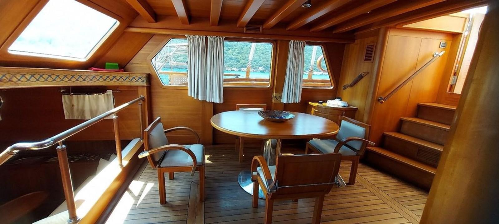 a room with a table chairs and a bench aboard SYY Yacht for Sale