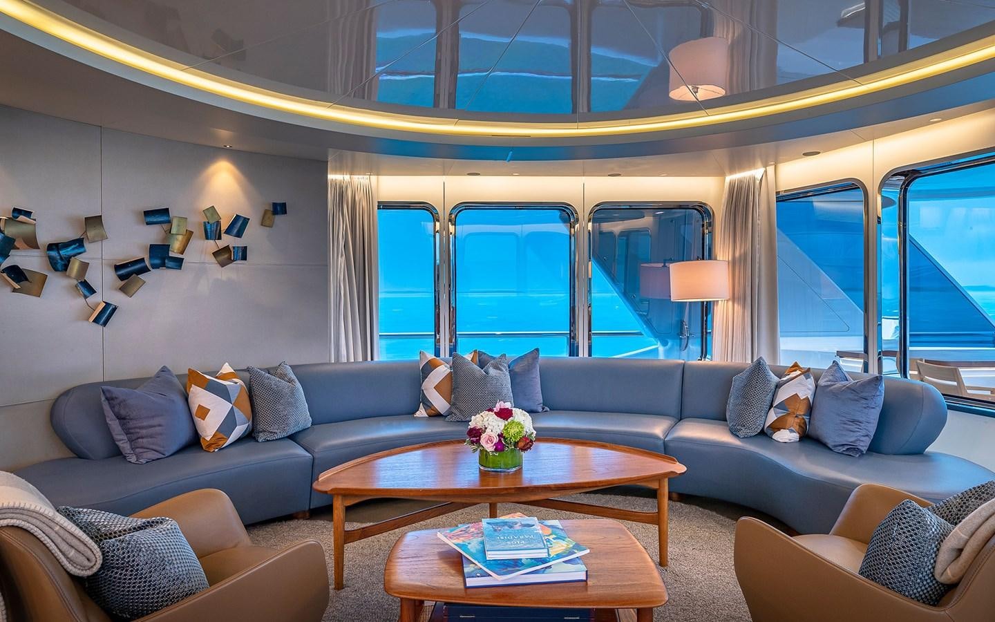 a living room with a blue couch and a large window aboard REVERIE Yacht for Sale