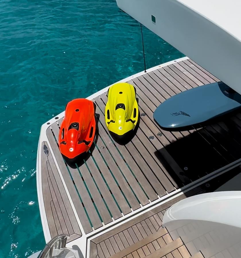 a yellow and black boat on a deck next to a large body of water aboard SOLARIS Yacht for Sale