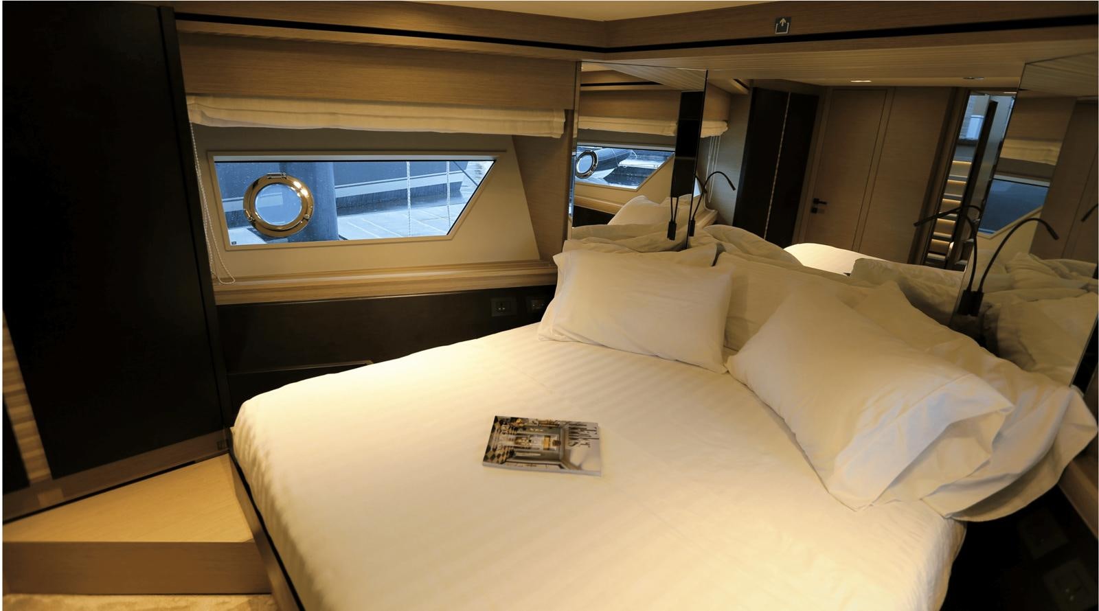 a bed with a white sheet and a round mirror on the wall aboard 2020 FERRETTI 670 Yacht for Sale