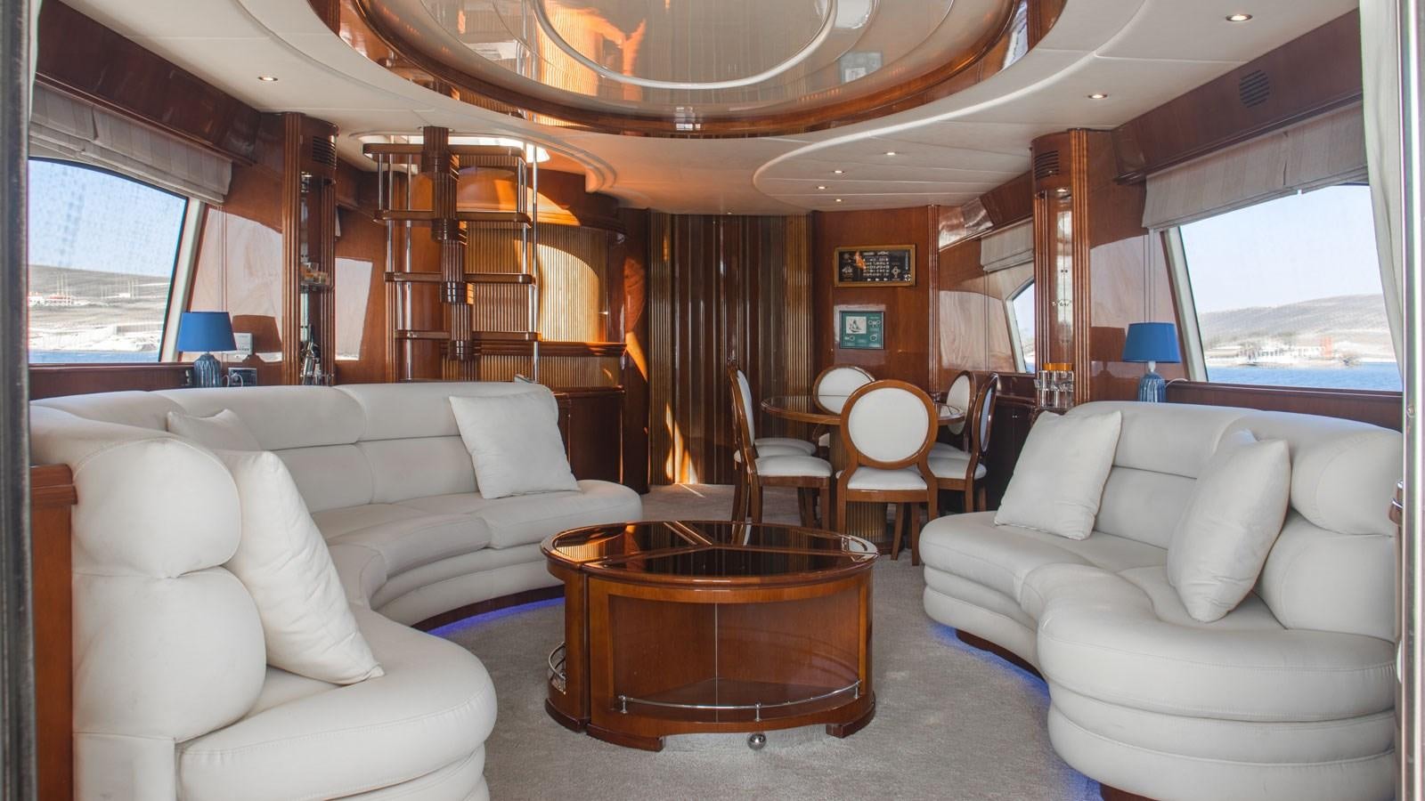 a living room with a large wood table and chairs aboard TITAN Yacht for Sale