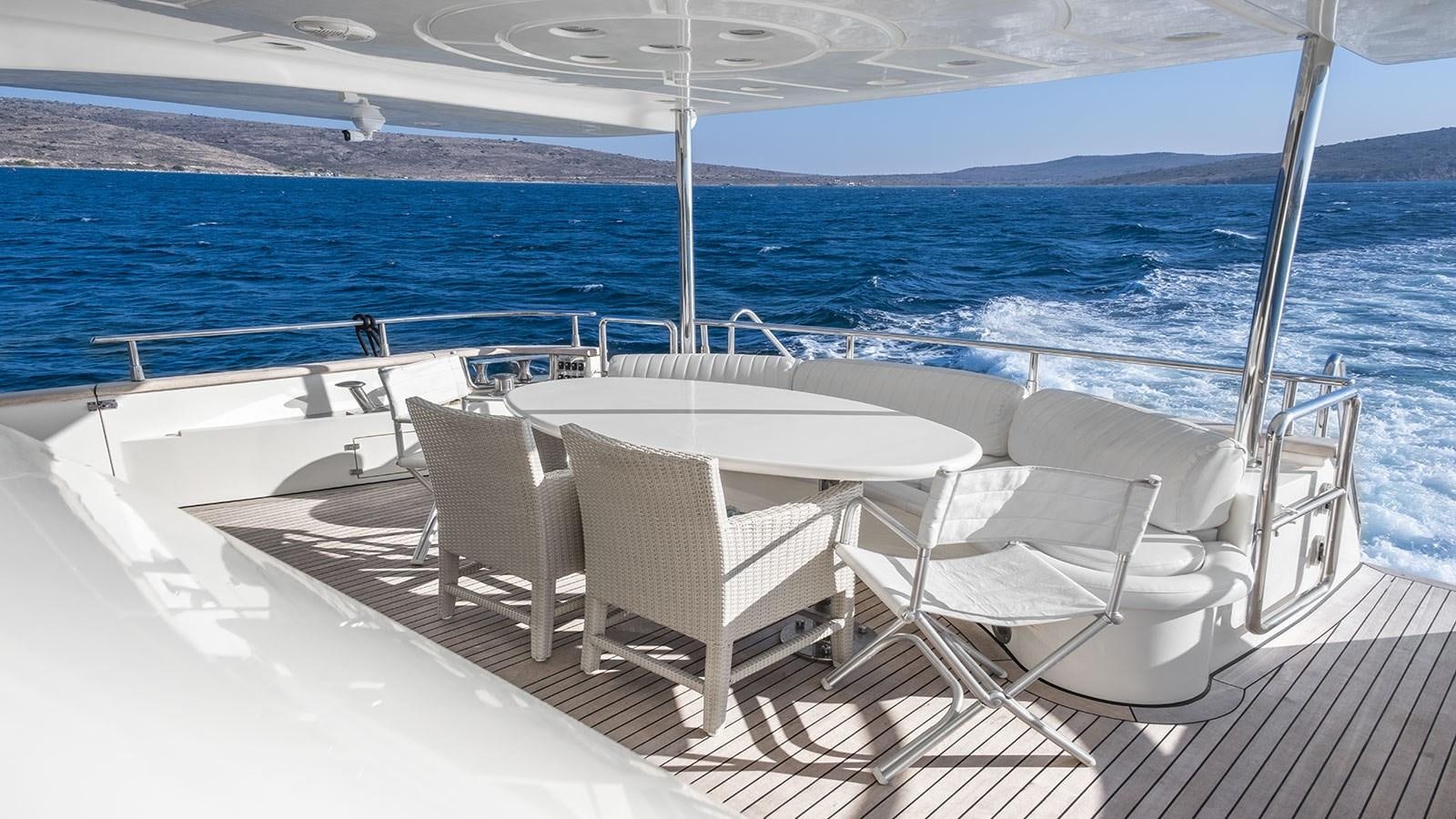 a white table and chairs on a deck overlooking a large body of water aboard TITAN Yacht for Sale