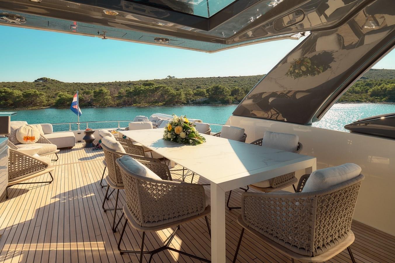 a table and chairs on a deck overlooking a body of water aboard DAMARI Yacht for Sale