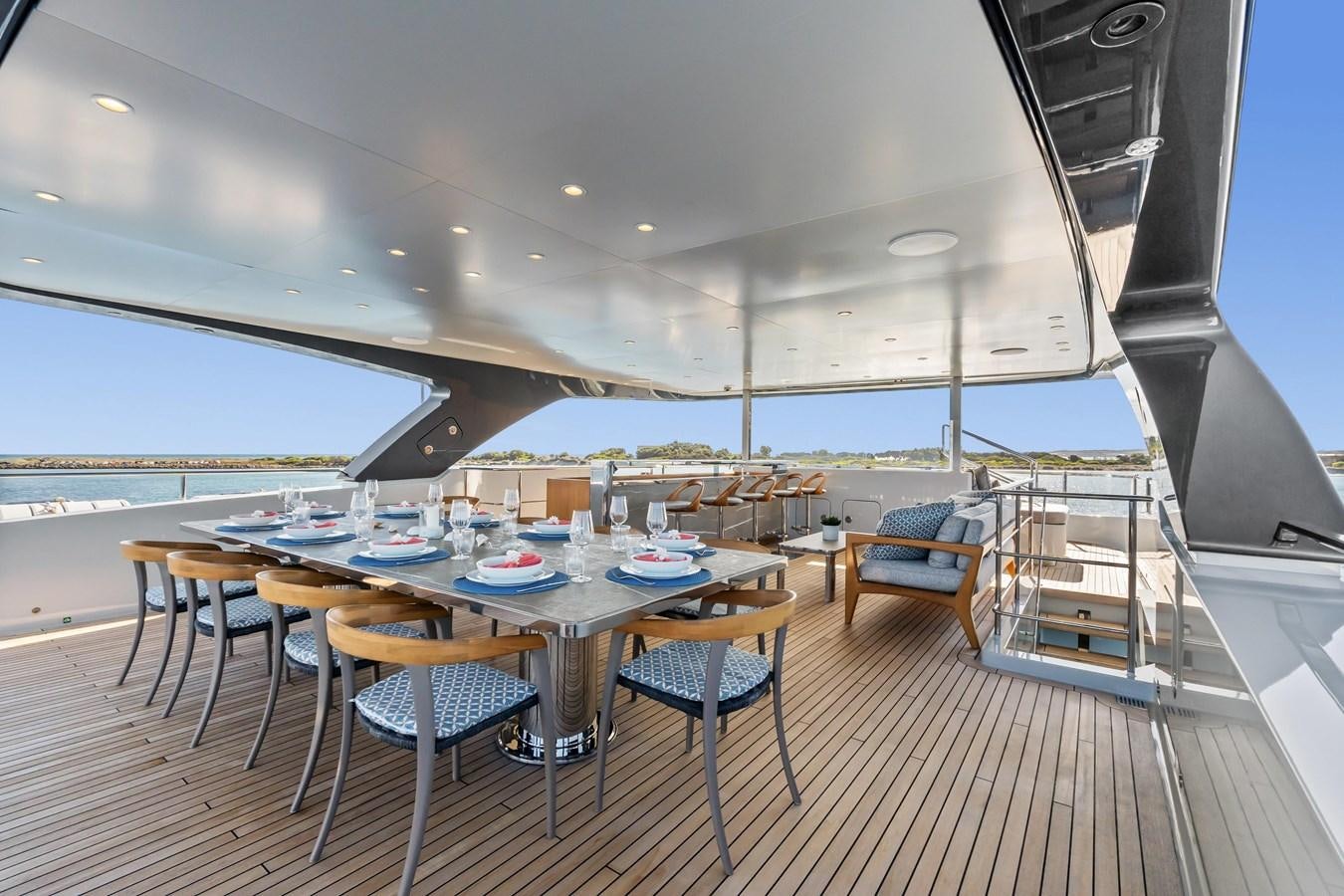 a large dining table with chairs and a large body of water in the background aboard GLOBAS Yacht for Sale