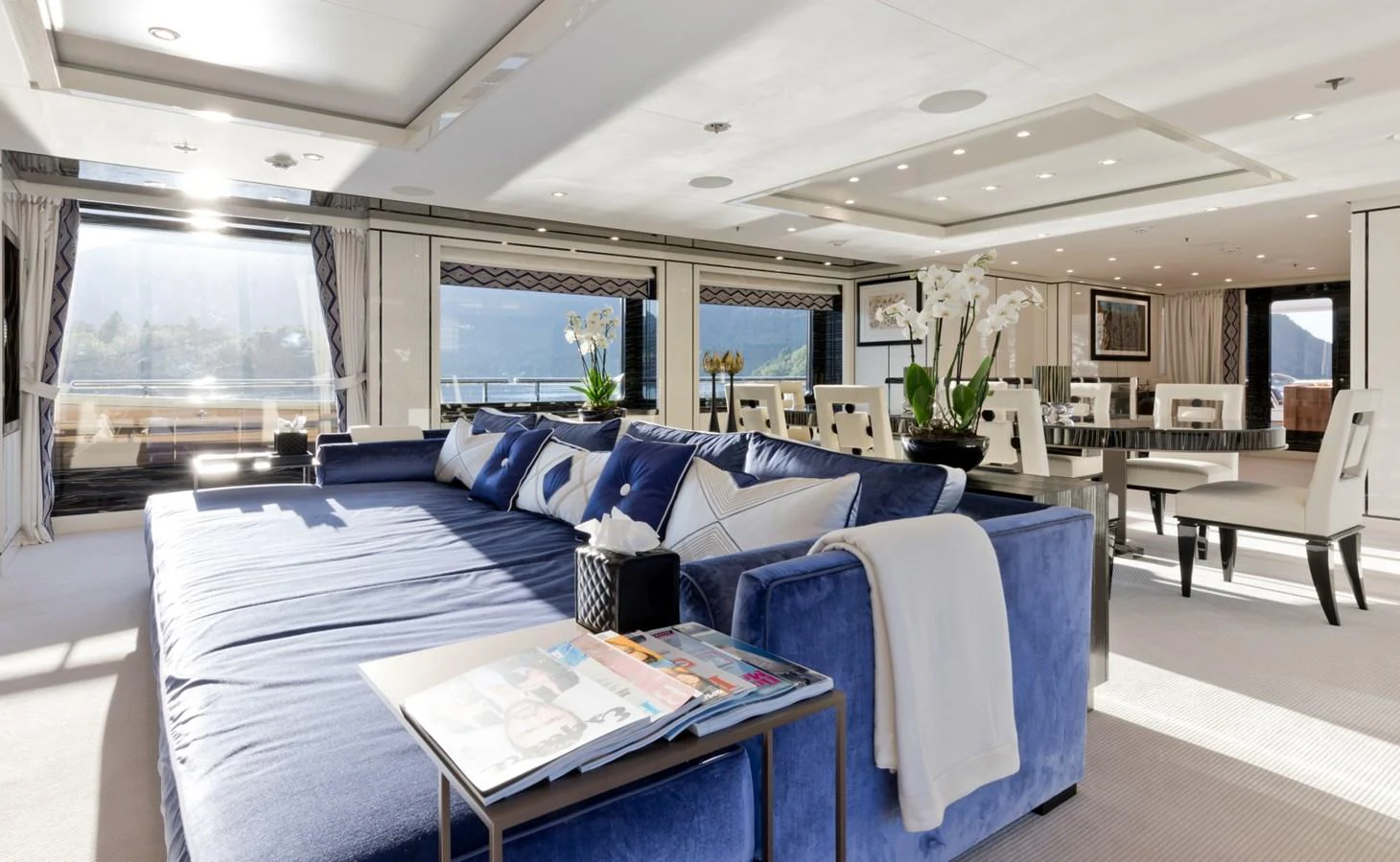 a large living room with a blue couch and a large window aboard LILI Yacht for Sale