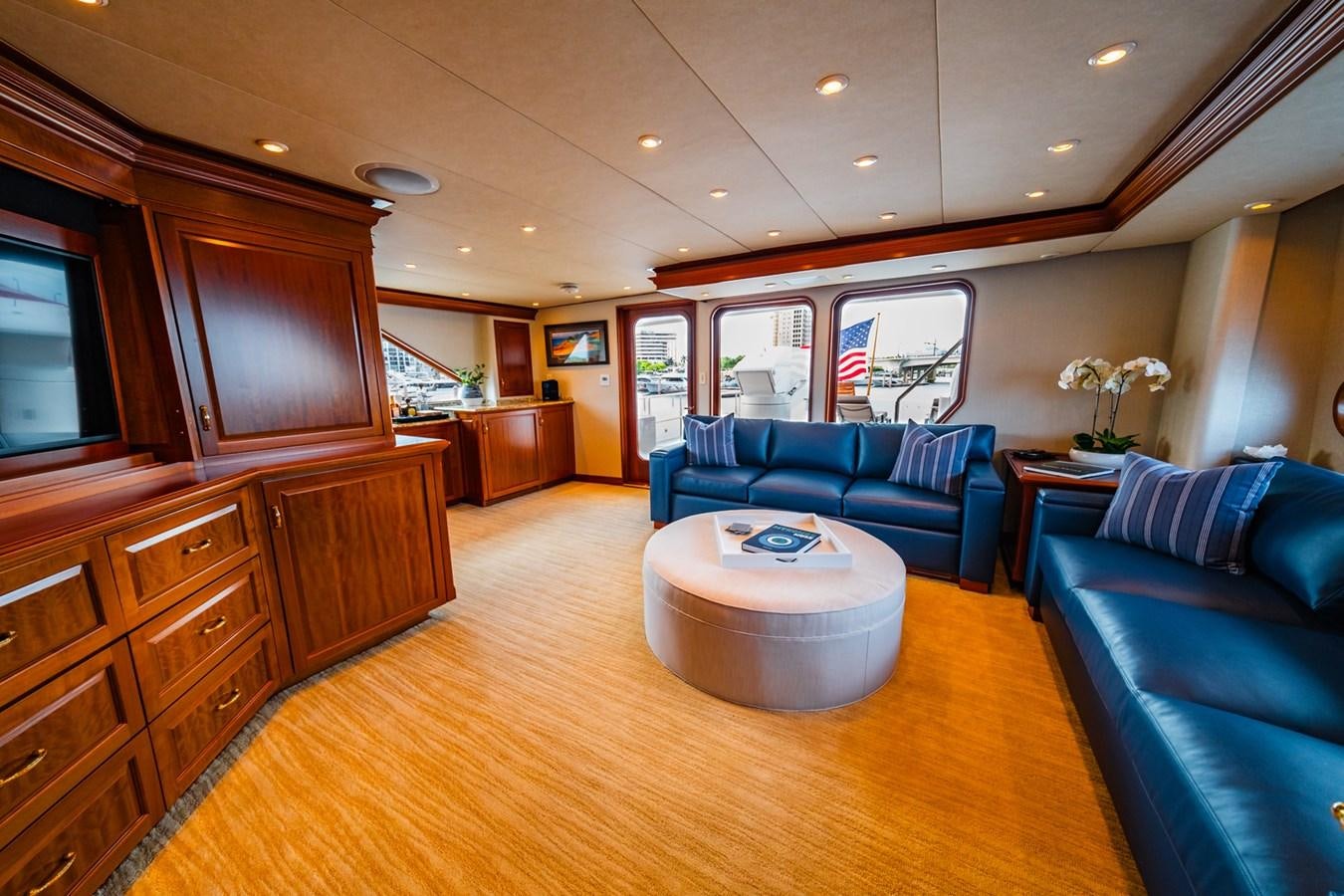 a living room with a large wood cabinet and a round table aboard IMPETUOUS Yacht for Sale
